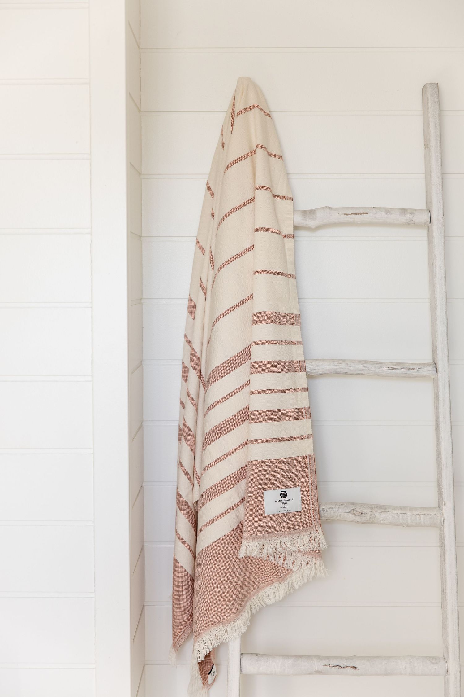 A series of beige and white striped Turkish cotton towels hanging on white walls showing different folding styles.