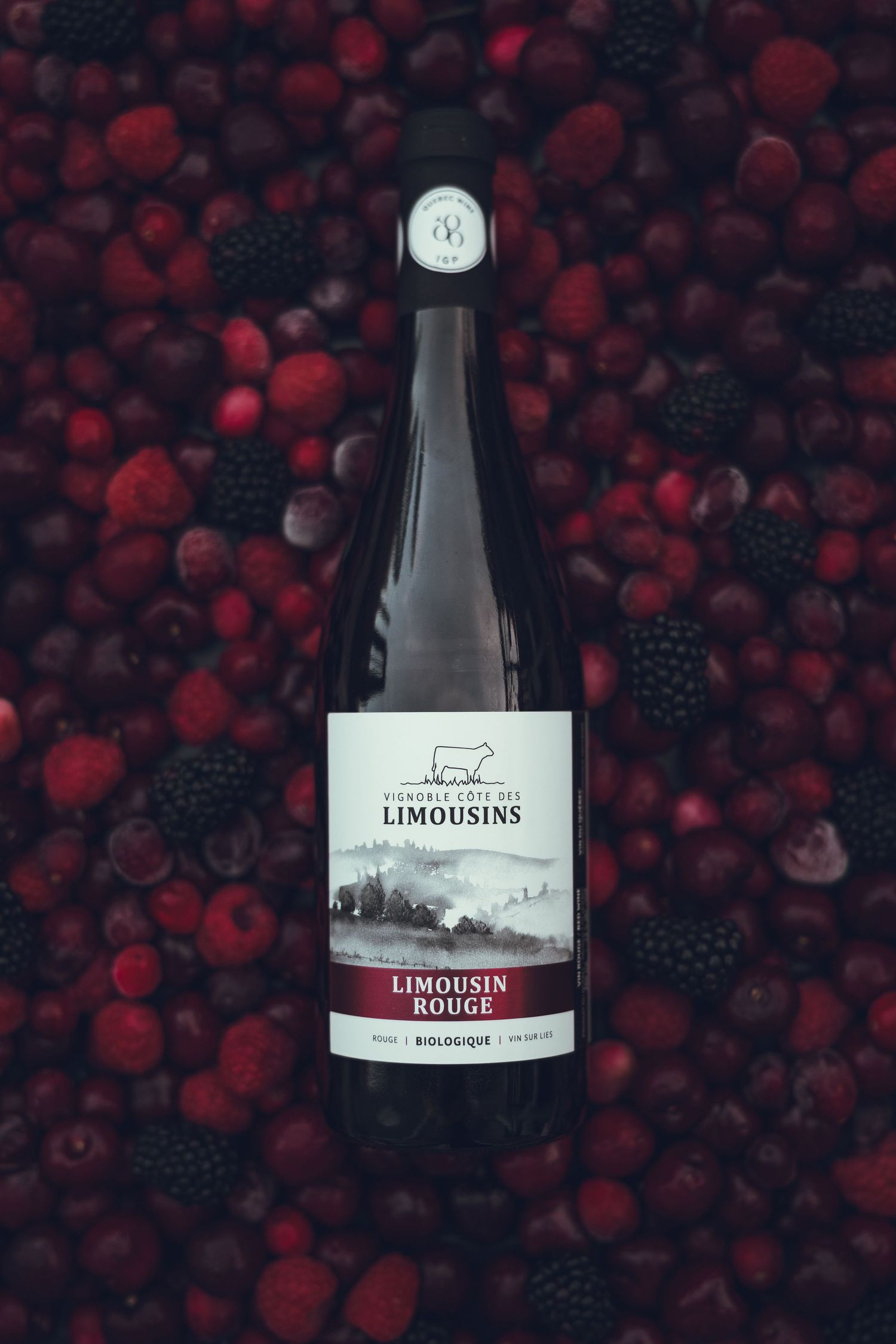 Wine bottle labeled Limousins Rouge displayed against a dark background of red berries.
