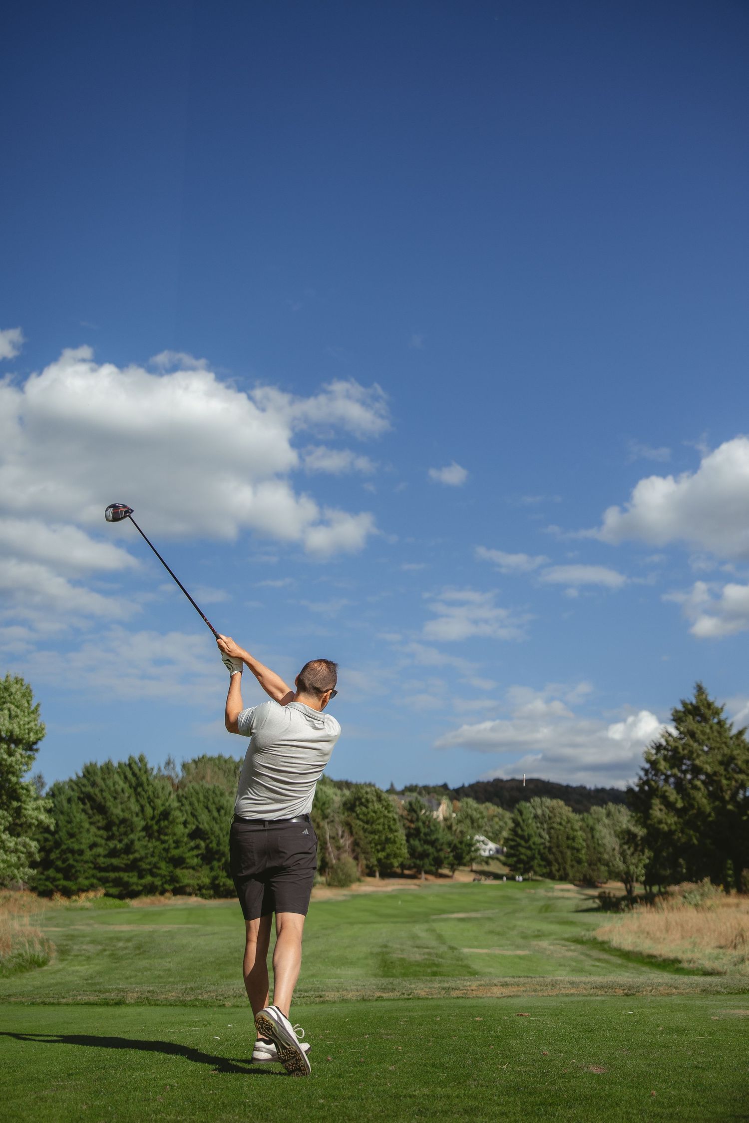 A sequence of golf swing photos showing follow-through motion on a sunny day at a golf course with blue skies.