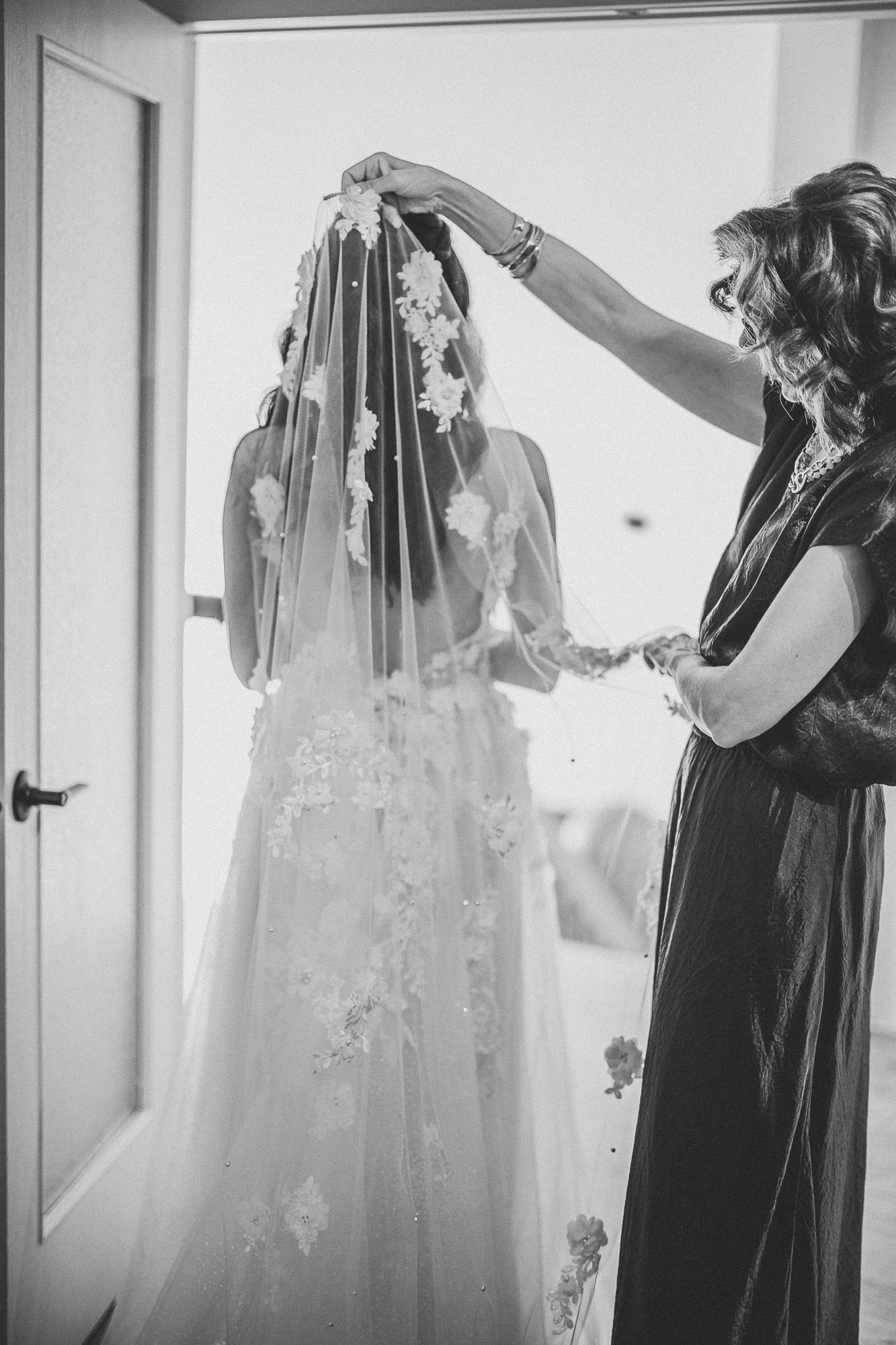 Photographie en noir et blanc montrant robes de mariée et tenues de demoiselles d’honneur suspendues lors des préparatifs