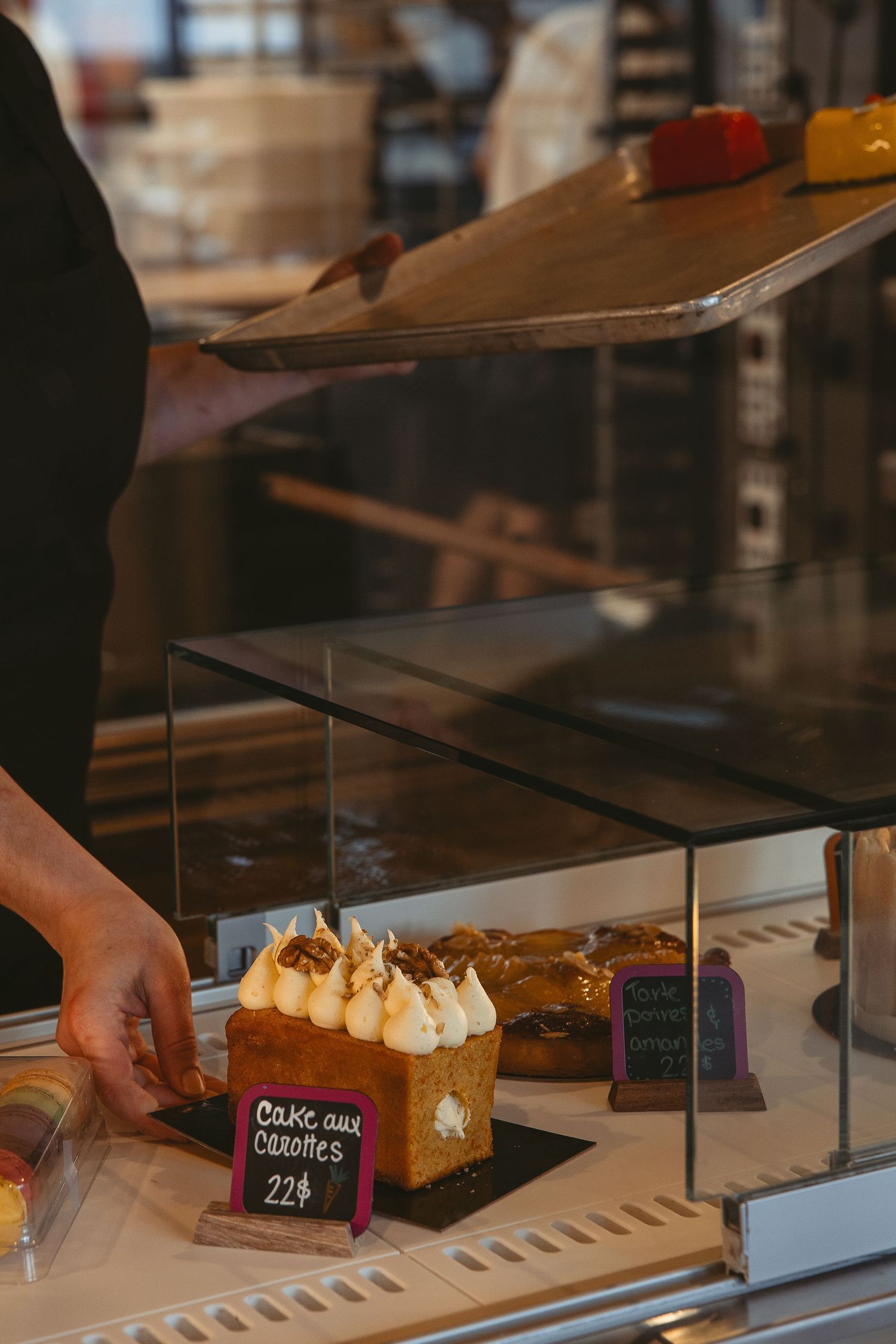 Pastry display case showing desserts with price tags in a bakery shop.