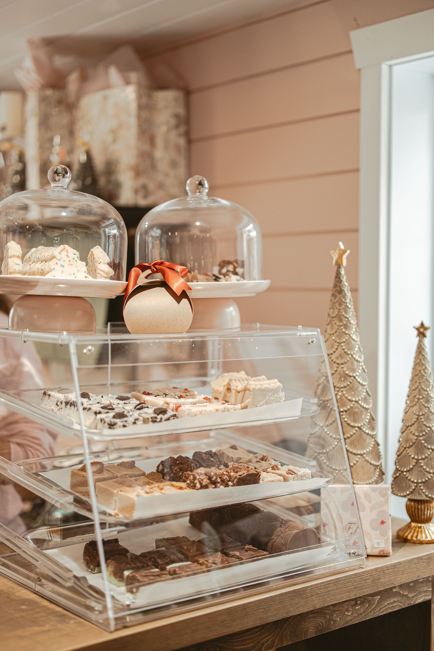 Elegant dessert display with tiered glass cases showcasing holiday treats and decorative gold trees.