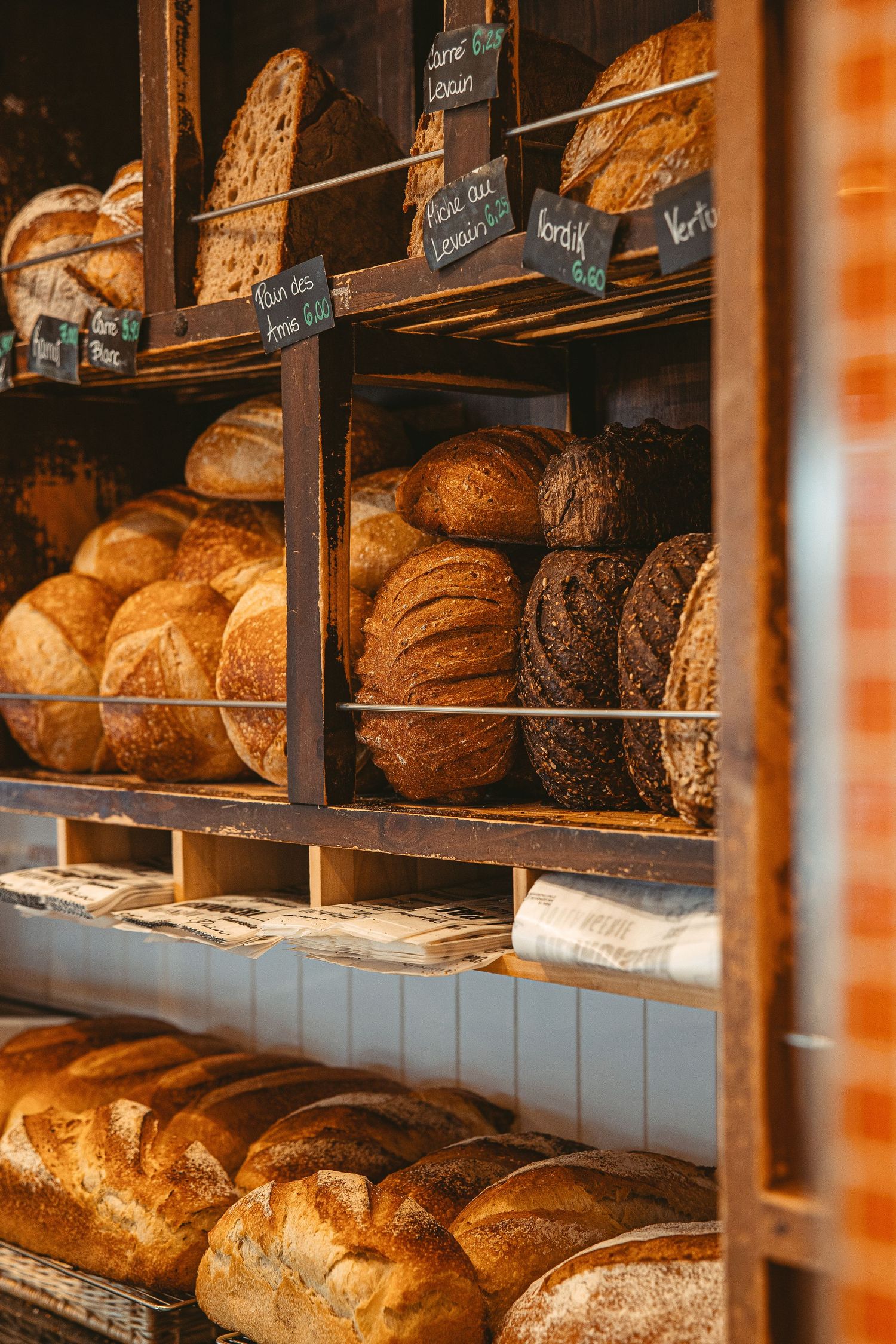 Freshly baked artisan bread loaves displayed on wooden bakery shelves.