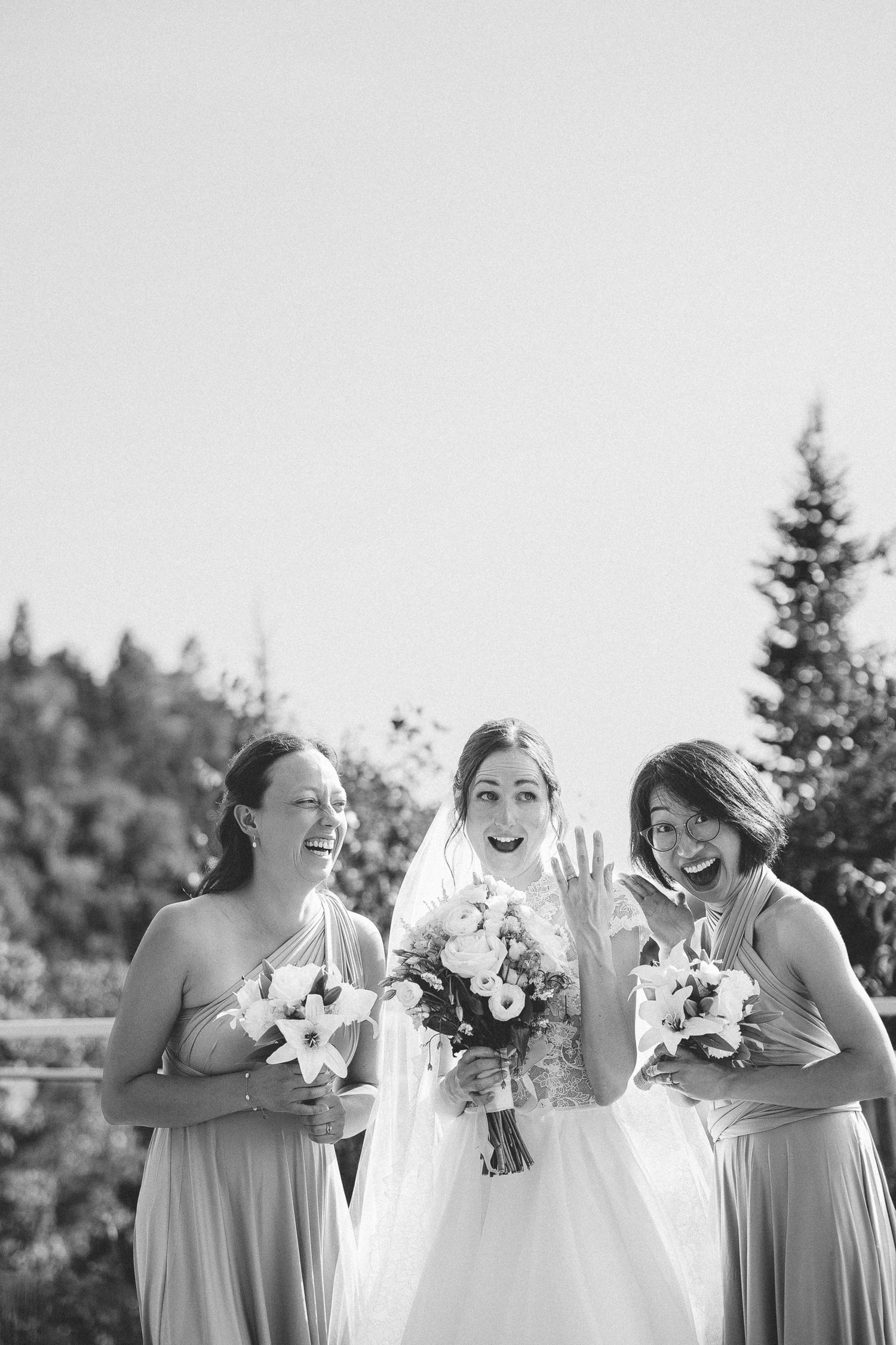 Noir et blanc Demoiselles d’honneur tenant des bouquets blancs, aux côtés de la mariée en robe blanche lors d’une cérémonie extérieure.