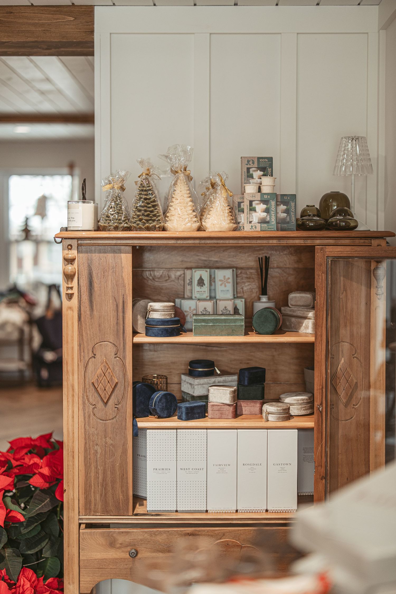 Wooden retail display shelving with white storage boxes and red poinsettias for holiday decor.