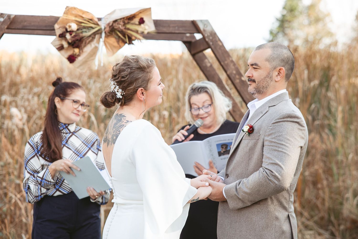Échange de voeux lors d'un mariage en plein air au cœur d’une forêt automnale, baignée d’une lumière dorée filtrant à travers les arbres.