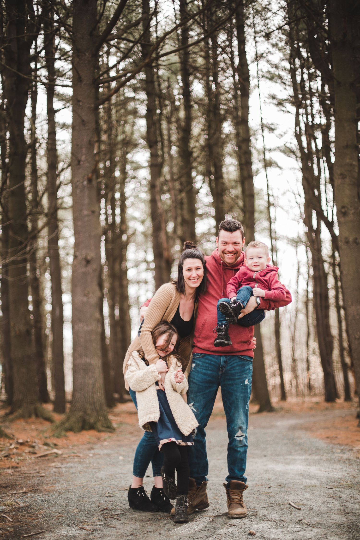 Famille heureuse jouant et riant sur sentier forestier en automne, capturée pour valoriser complicité, joie et moments chaleureux