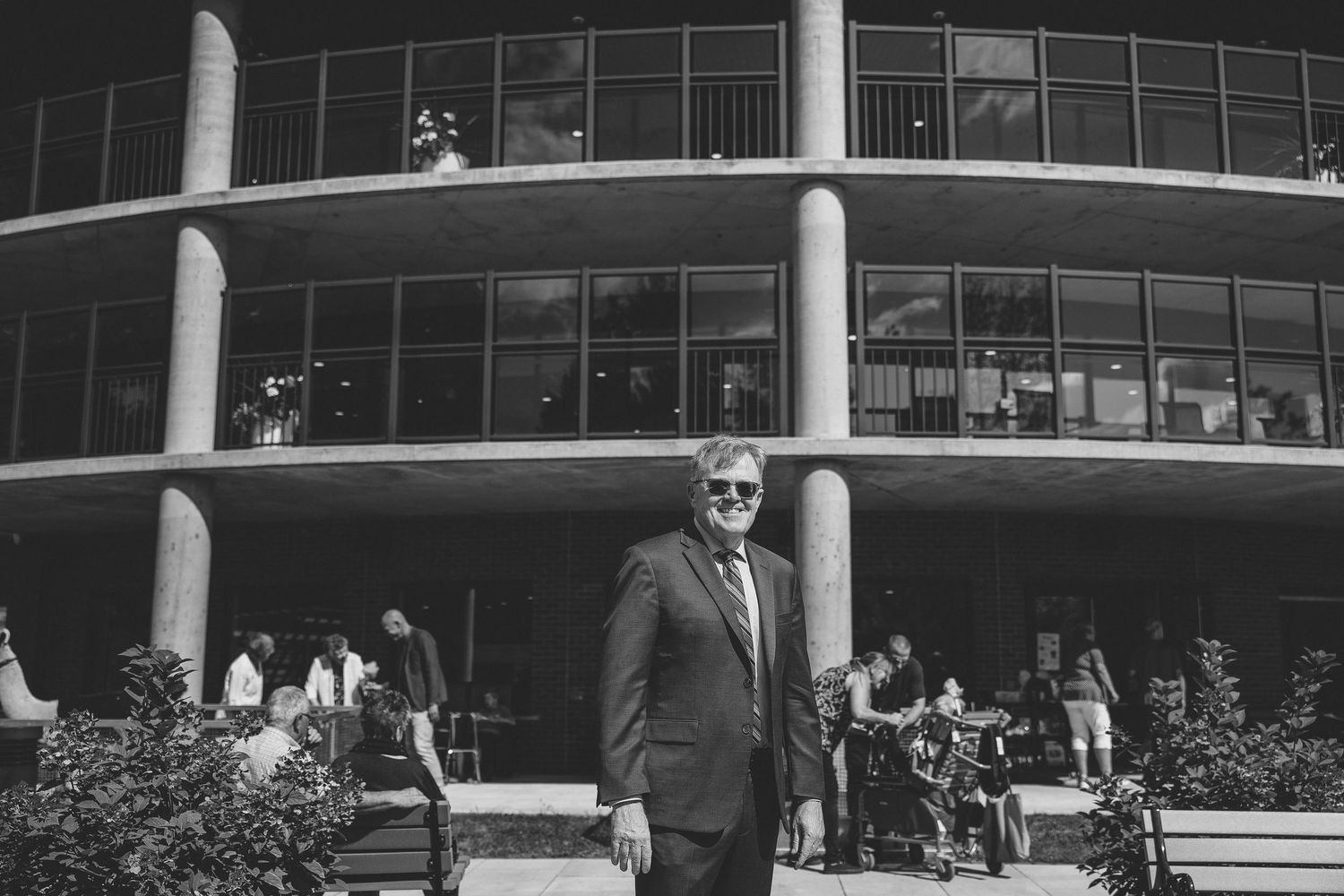 A black and white panoramic photograph of a mid-century modern office building with curved glass windows and columns.