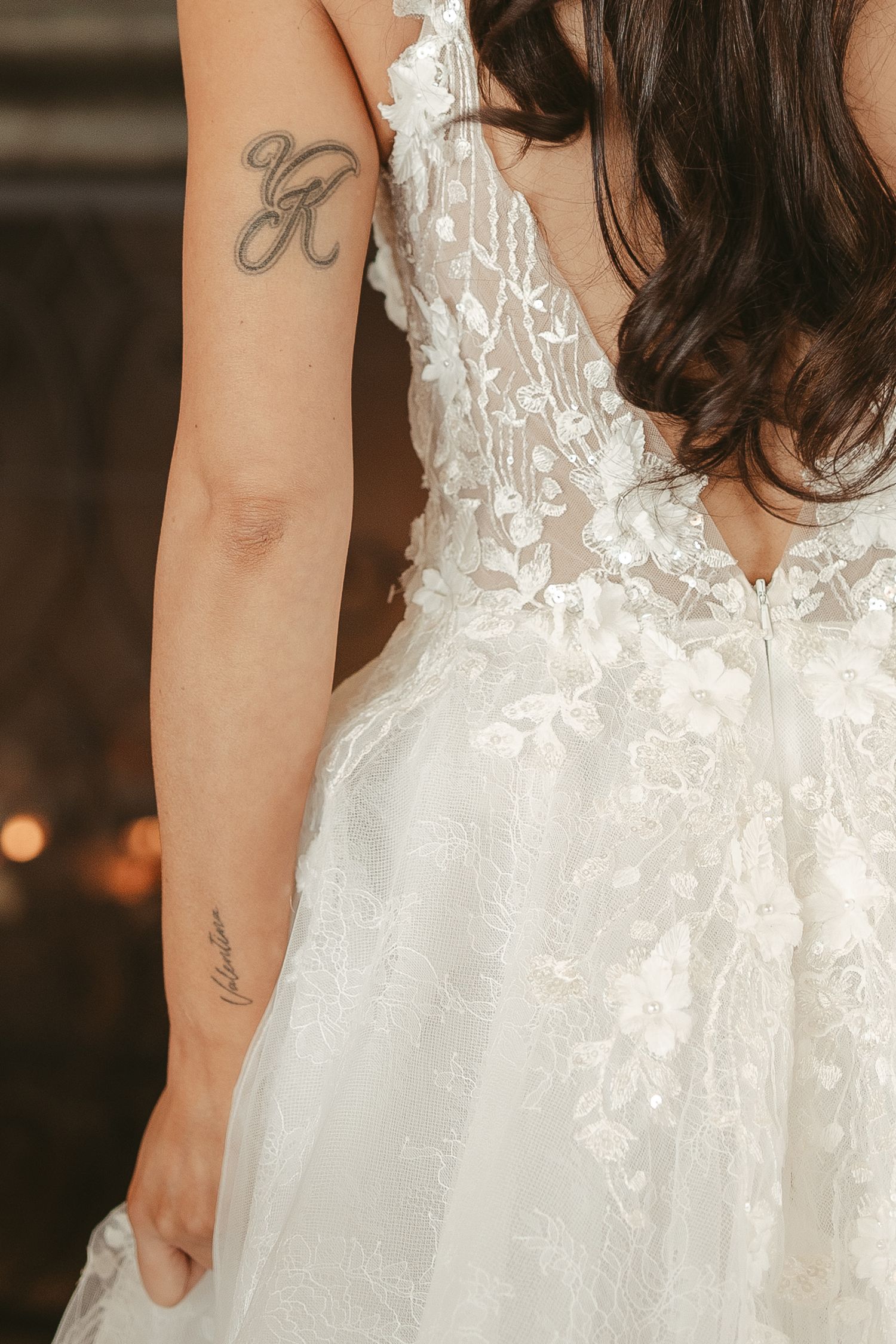 Close-up detail of delicate white lace on a wedding dress with floral patterns and intricate beadwork.