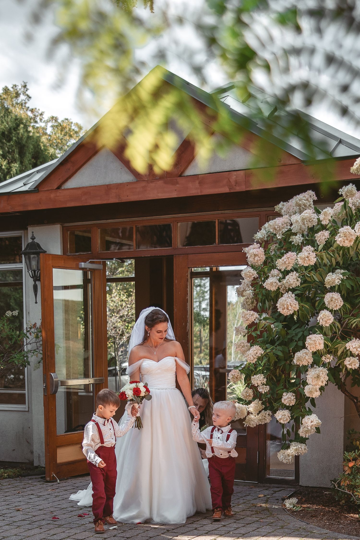 Wedding party poses in front of rustic venue with climbing roses and wooden beams.