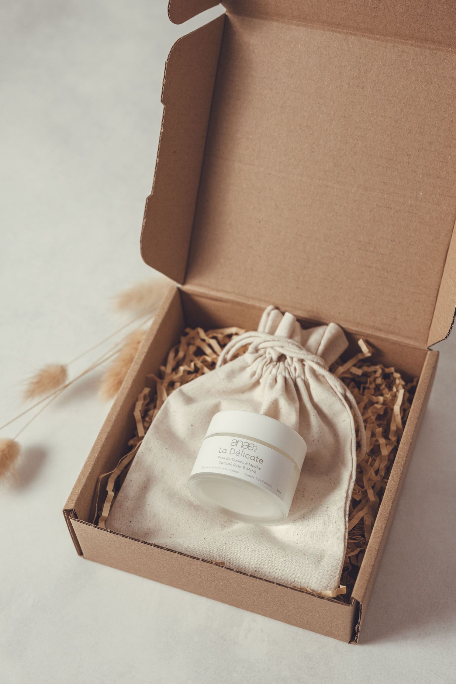 A series of cardboard gift boxes with cream colored drawstring pouches and natural wood filler arranged in sequence.