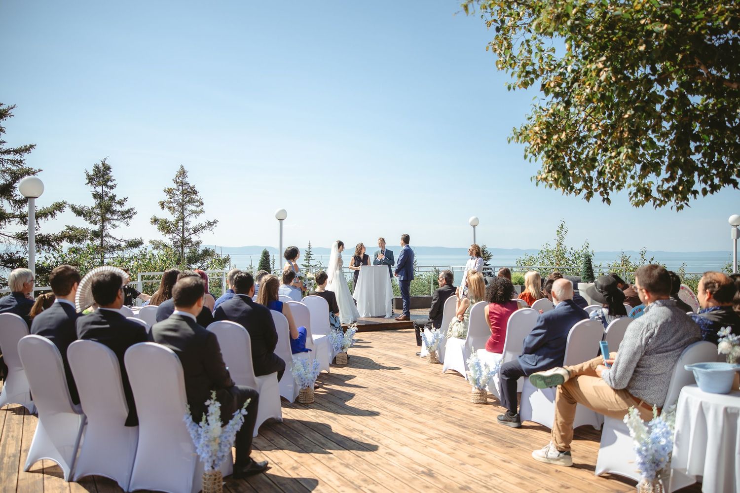 Cérémonie de mariage en plein air surplombant le lac Tahoe, avec chaises blanches et décor naturel par une journée ensoleillée.