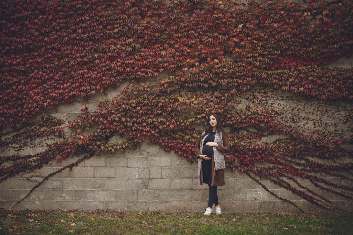 Photographie artistique : femme enceinte devant mur de briques rouges avec lierre grimpant, pour moments élégants et composition architectur