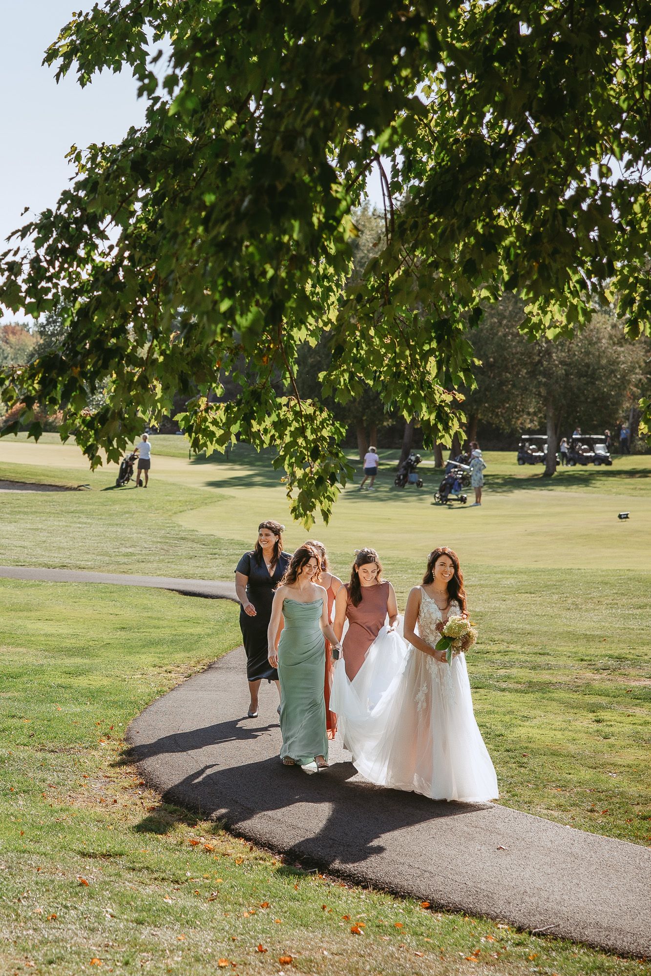 Cortège de mariage marchant sur un sentier bordé d’arbres dans un parc lors d’une journée d’automne ensoleillée, en Estrie