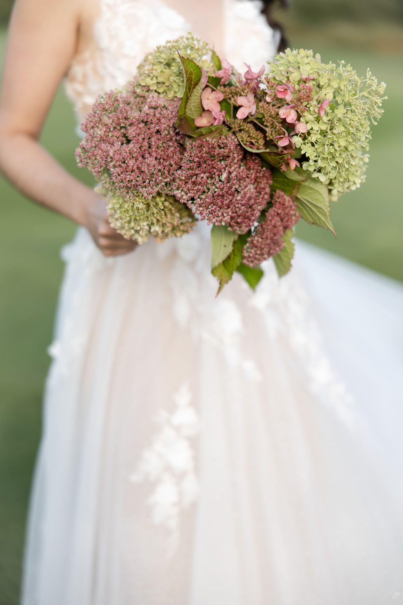 Série de bouquets de mariage avec hortensias roses et crème tenus contre des robes blanches, en lumière naturelle douce