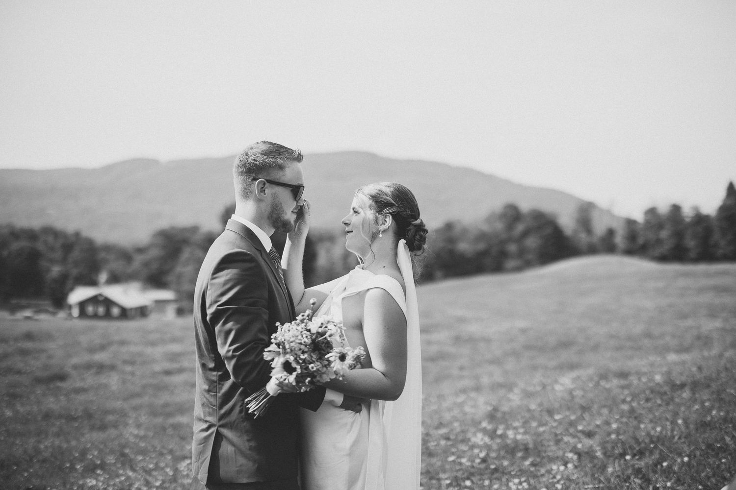 Série de photos de mariage en noir et blanc montrant des moments intimes d’un couple dans un champ en extérieur