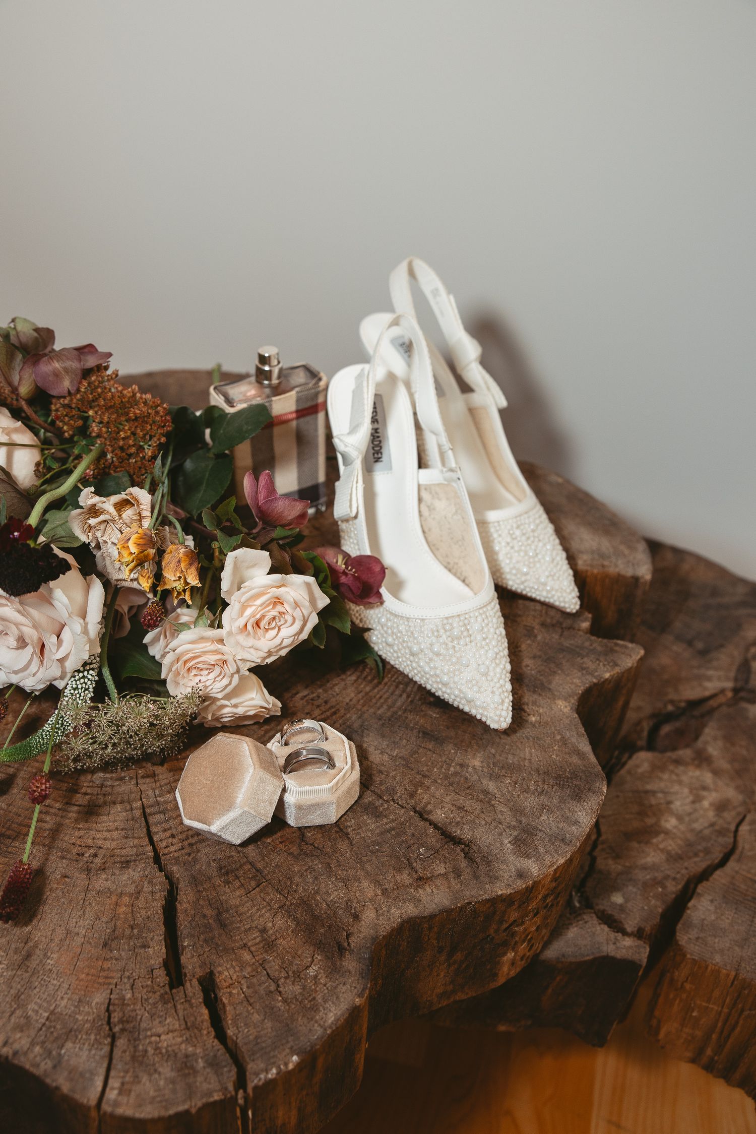 Chaussures de mariée blanches et compositions florales délicates disposées sur des billots de bois, détail raffiné du mariage.