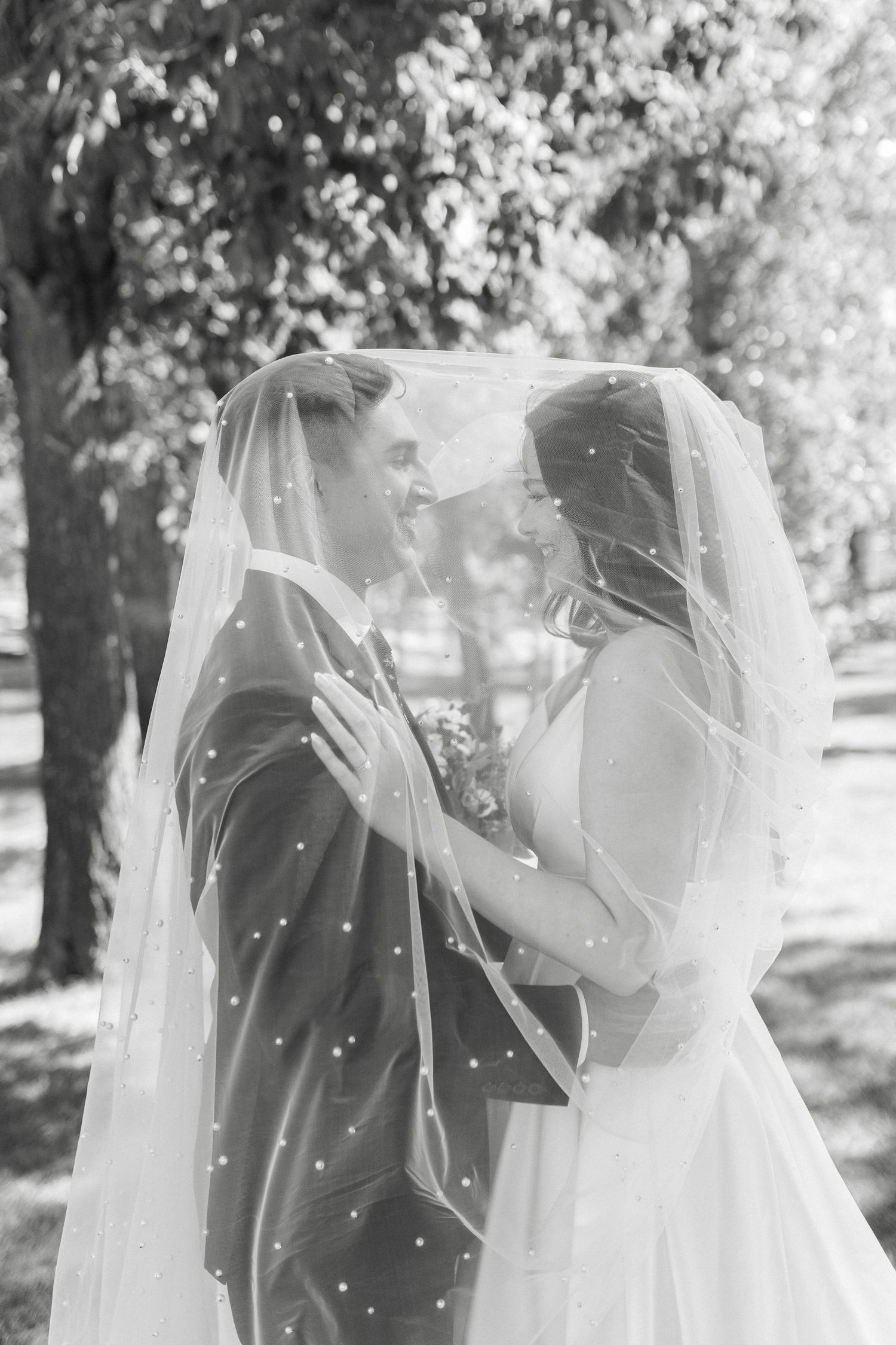 A romantic black and white wedding photo sequence showing a couple sharing intimate moments under a flowing veil.