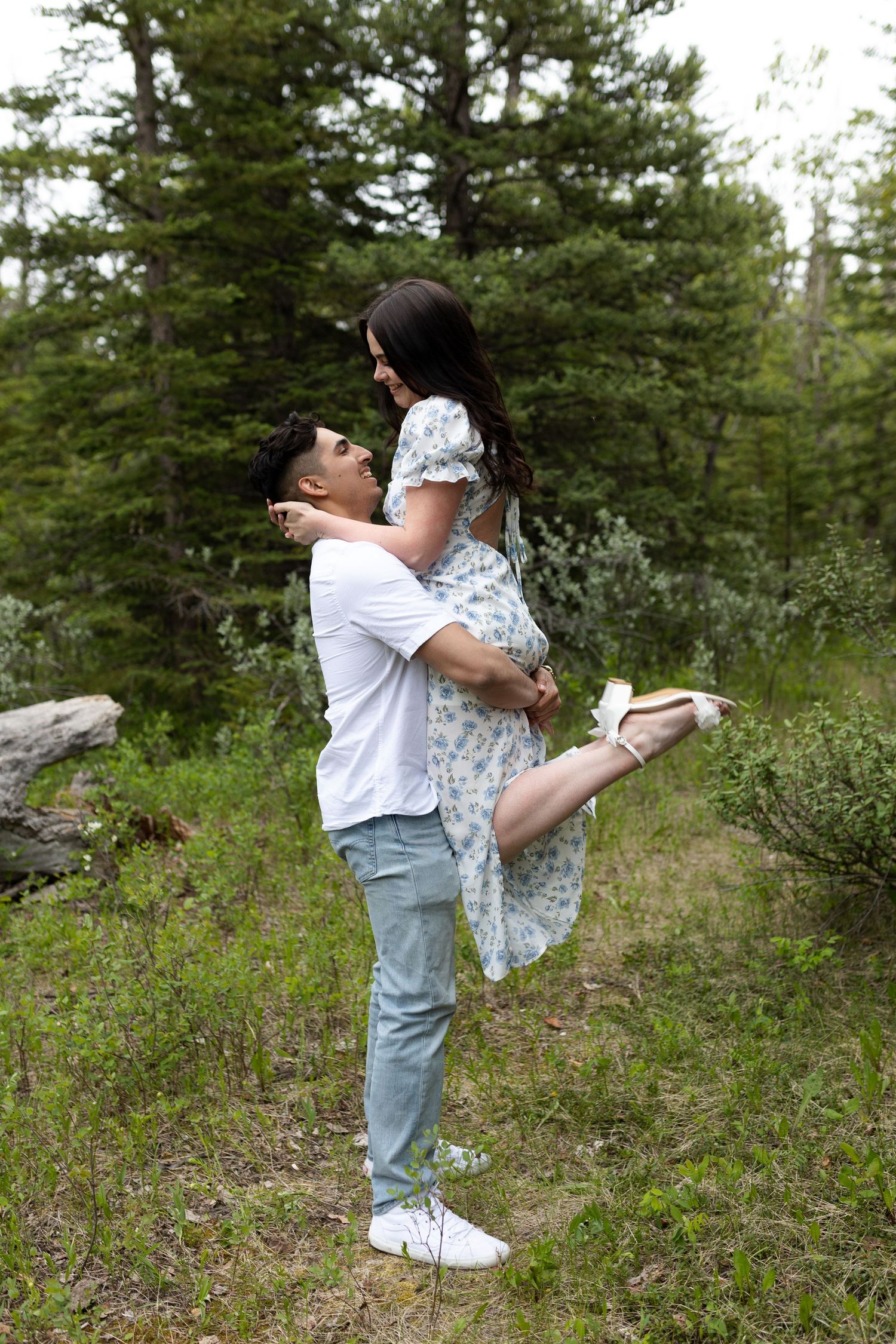 Playful dancing pose in a mountain meadow with pine trees in the background.