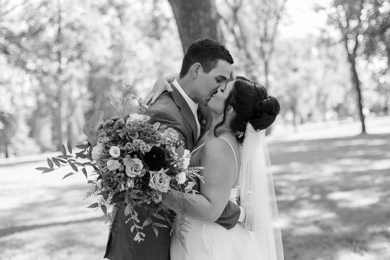 Black and white romantic wedding portraits captured in a natural outdoor setting.