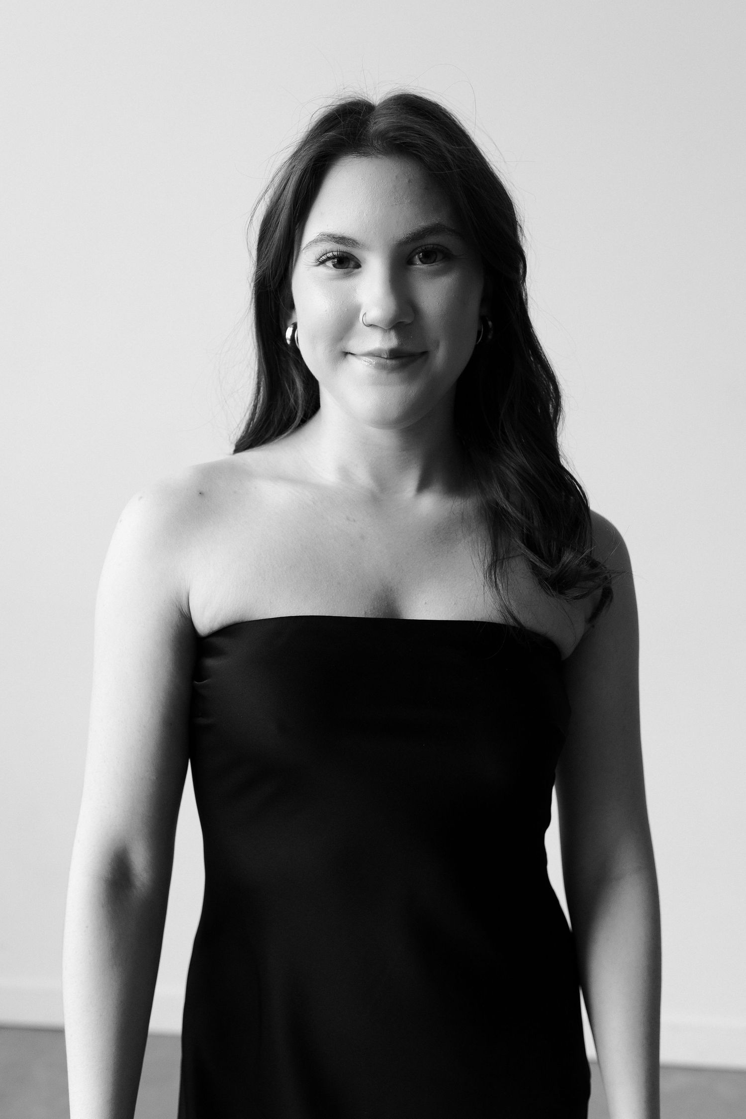 Black and white studio portrait showing elegant pose in strapless black dress.