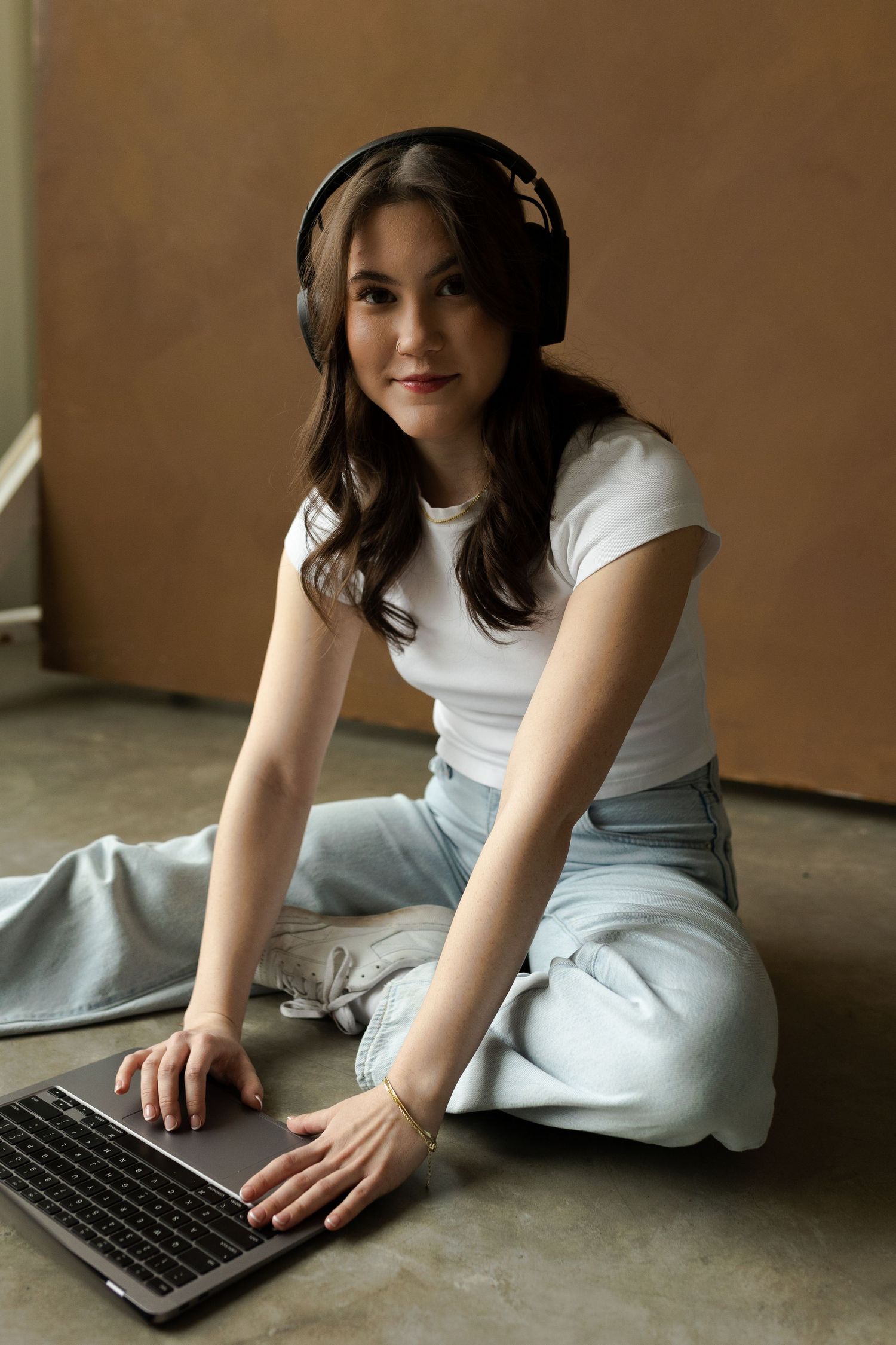 Person in white t-shirt working with keyboard while lying on concrete floor.