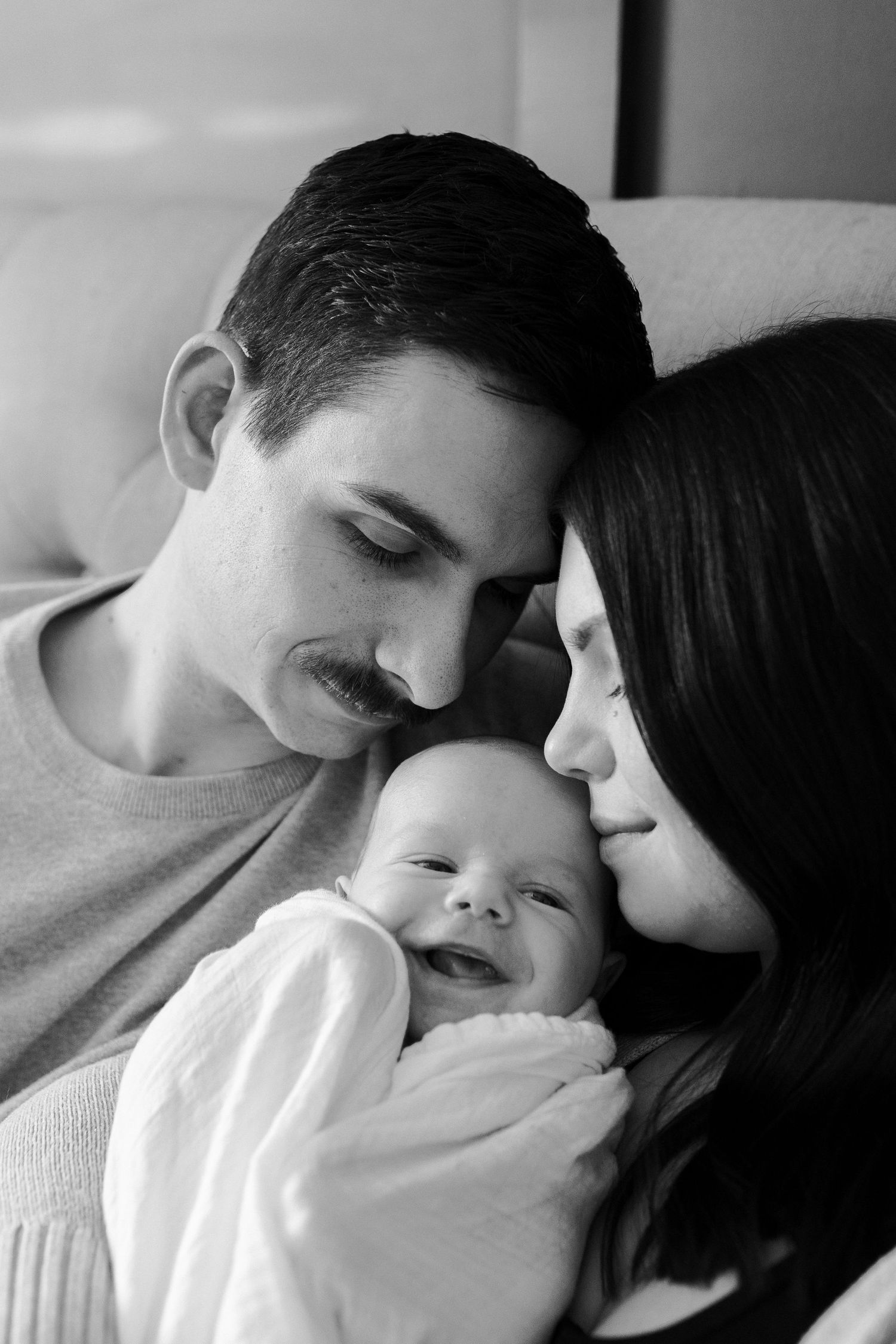 Black and white portrait of family sharing joyful moment with smiling baby.