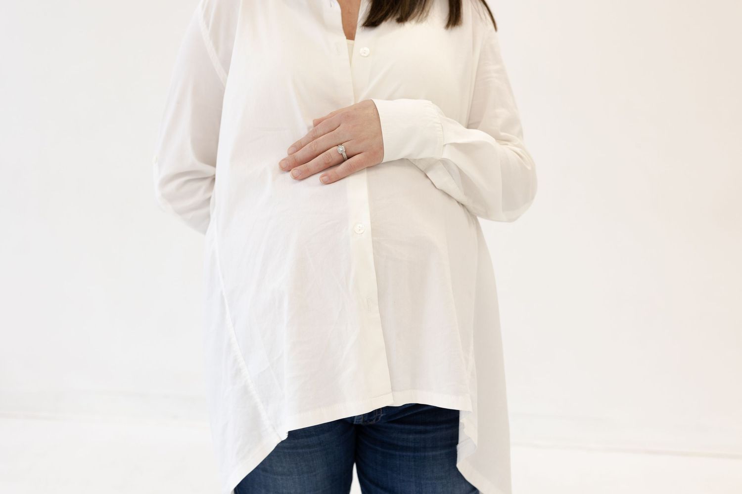 Lifestyle photoshoot featuring white button-down shirt and dark jeans in neutral setting.