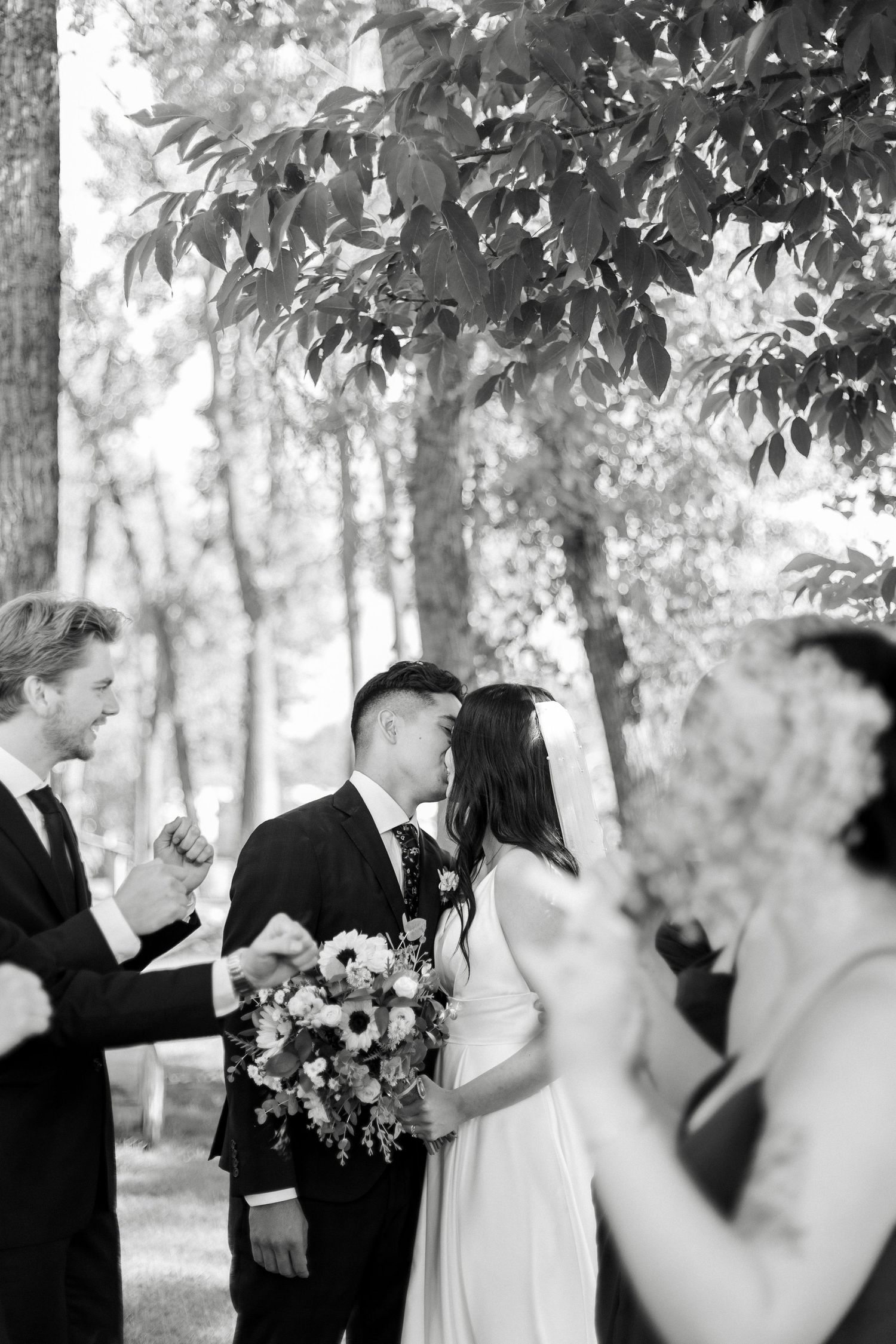 A romantic black and white wedding photo sequence showing a couple sharing intimate moments in a wooded setting.