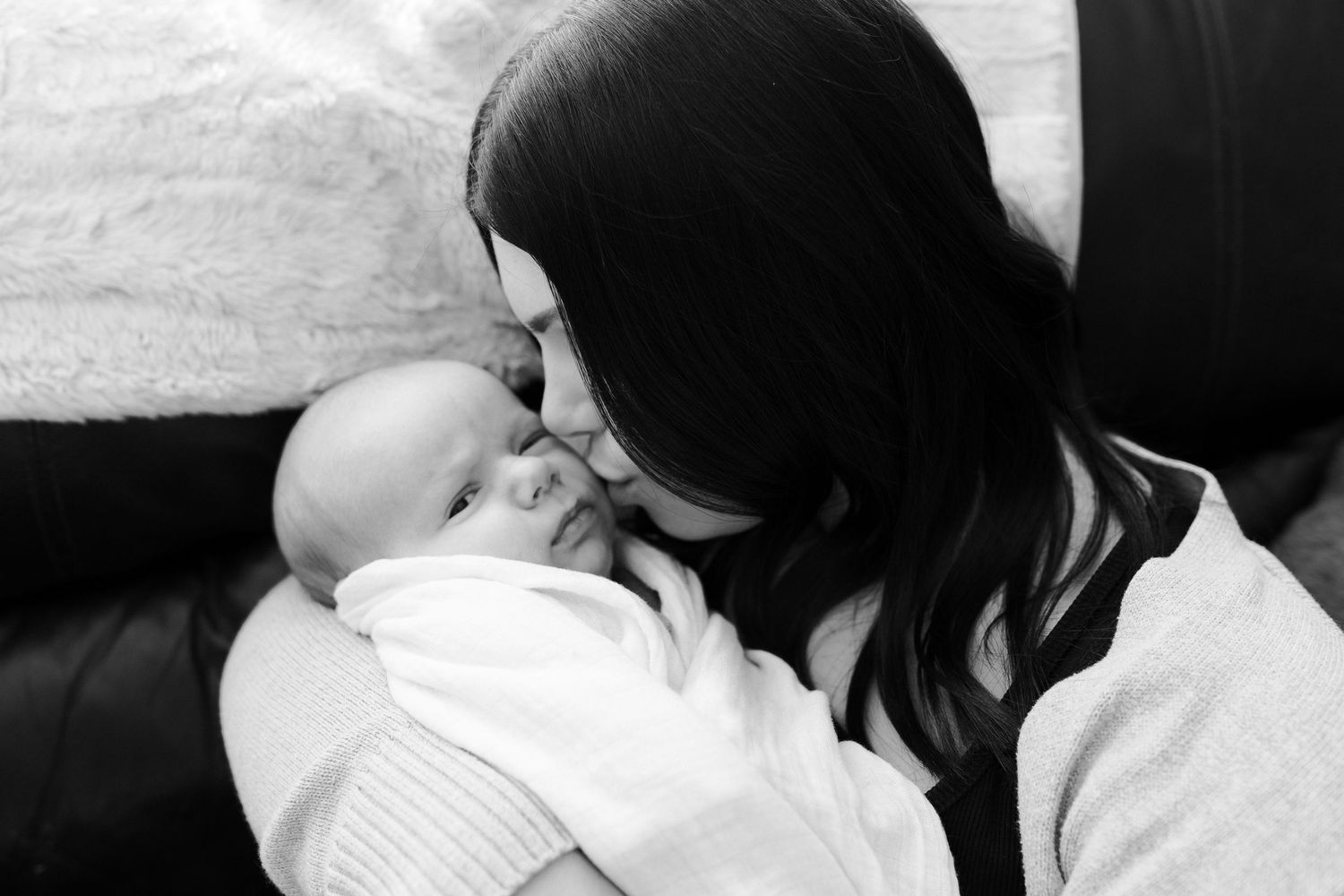 Black and white intimate portrait of mother and baby sharing tender moment.