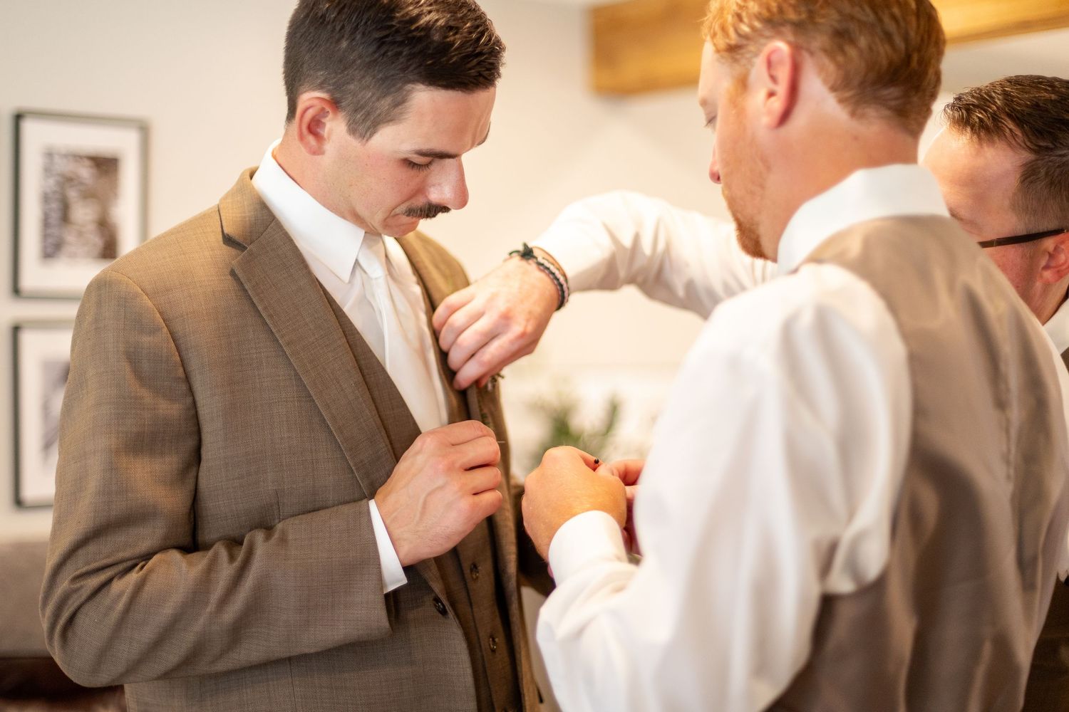 Wedding party members in suits and formal attire gathered indoors.