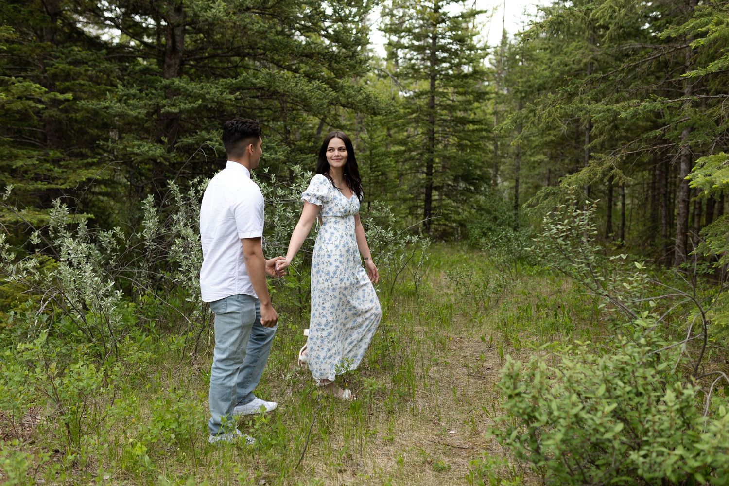 Couple walking together through a scenic evergreen forest path.