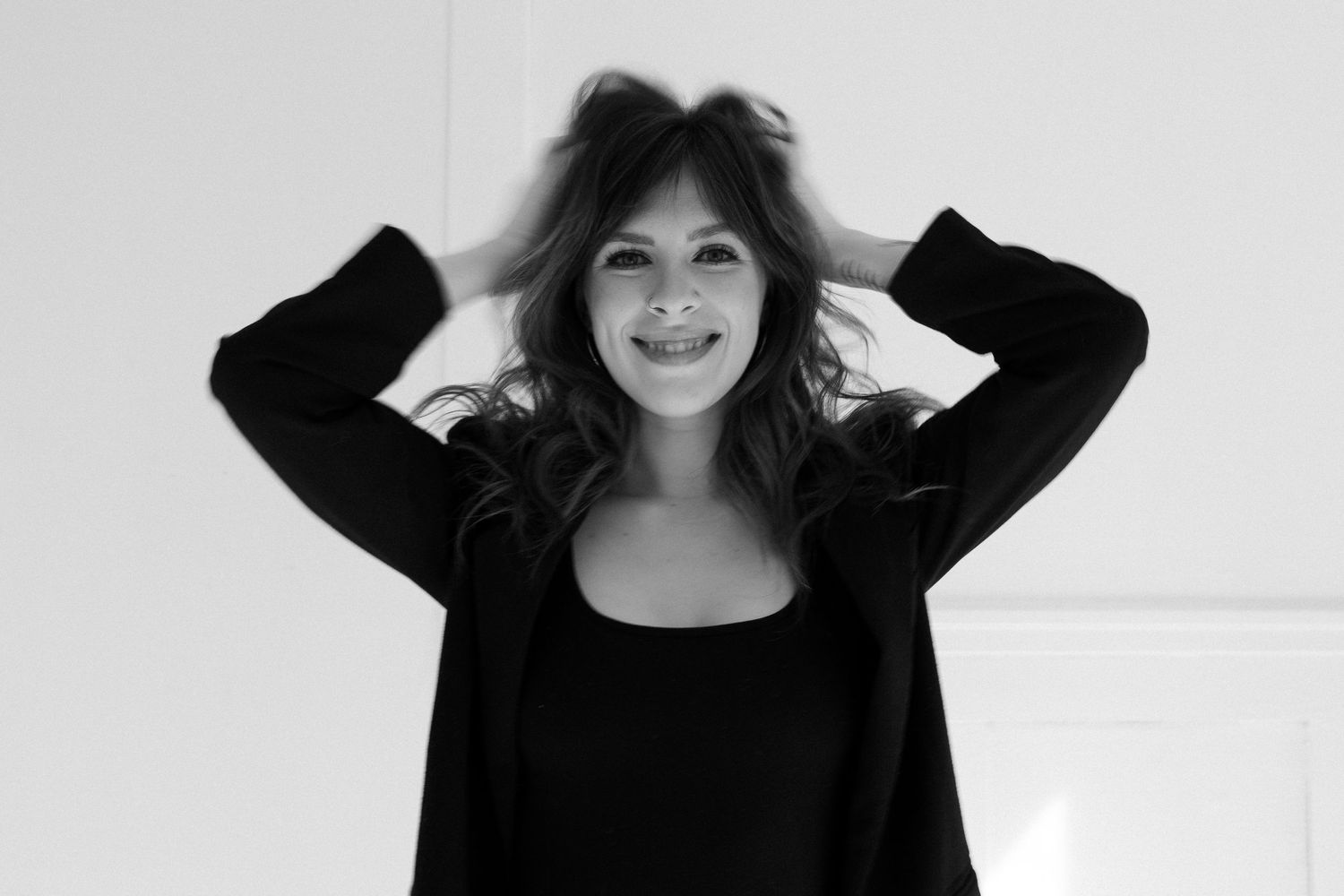 A person in black clothing making playful expressions against a white background.