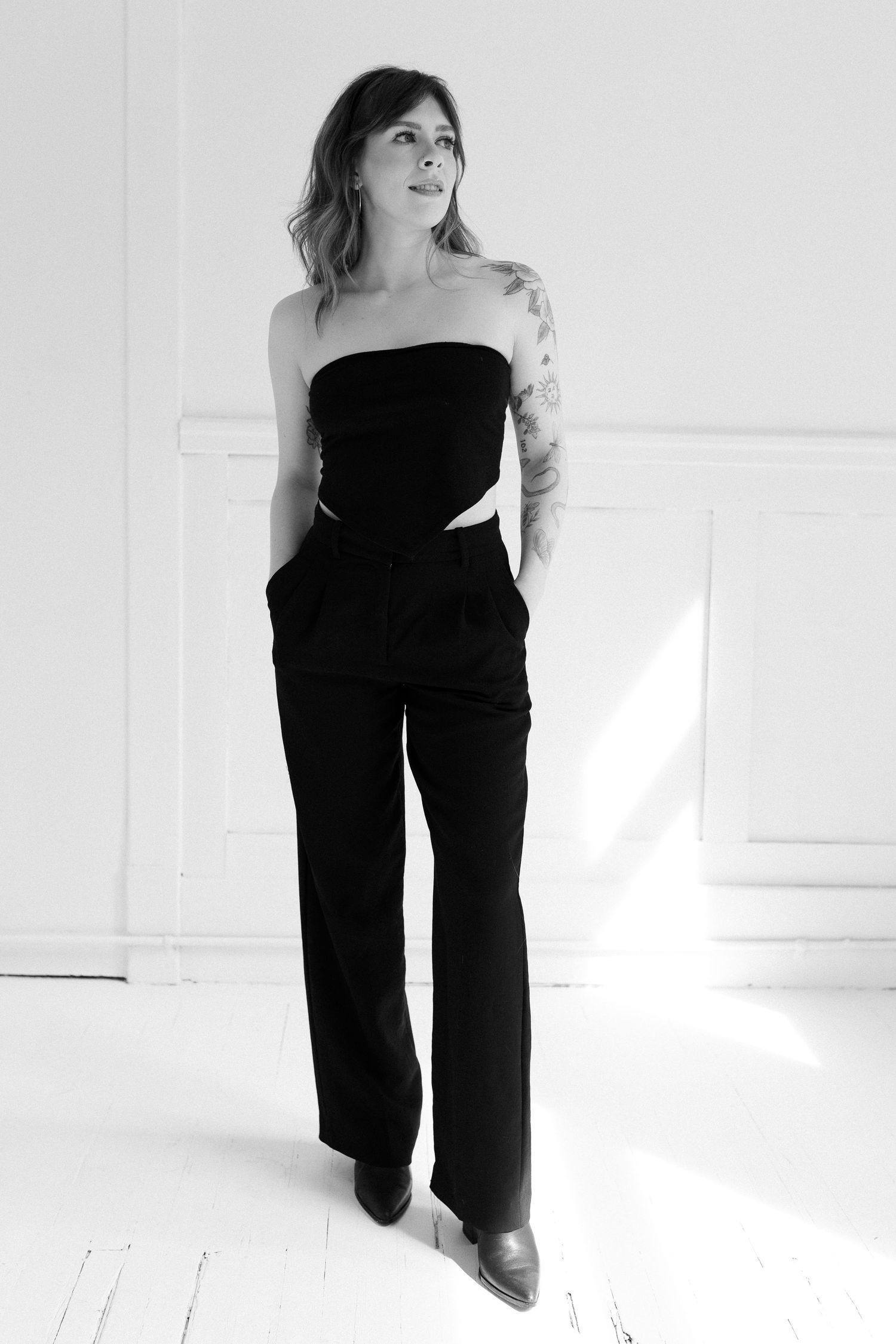 A person wearing black clothing posing on a white floor in various positions.
