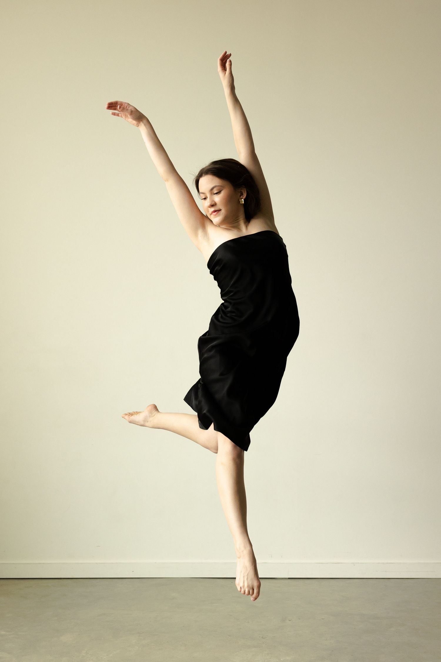 A dancer in black performs a graceful high kick against a light neutral background in a series of dynamic poses.