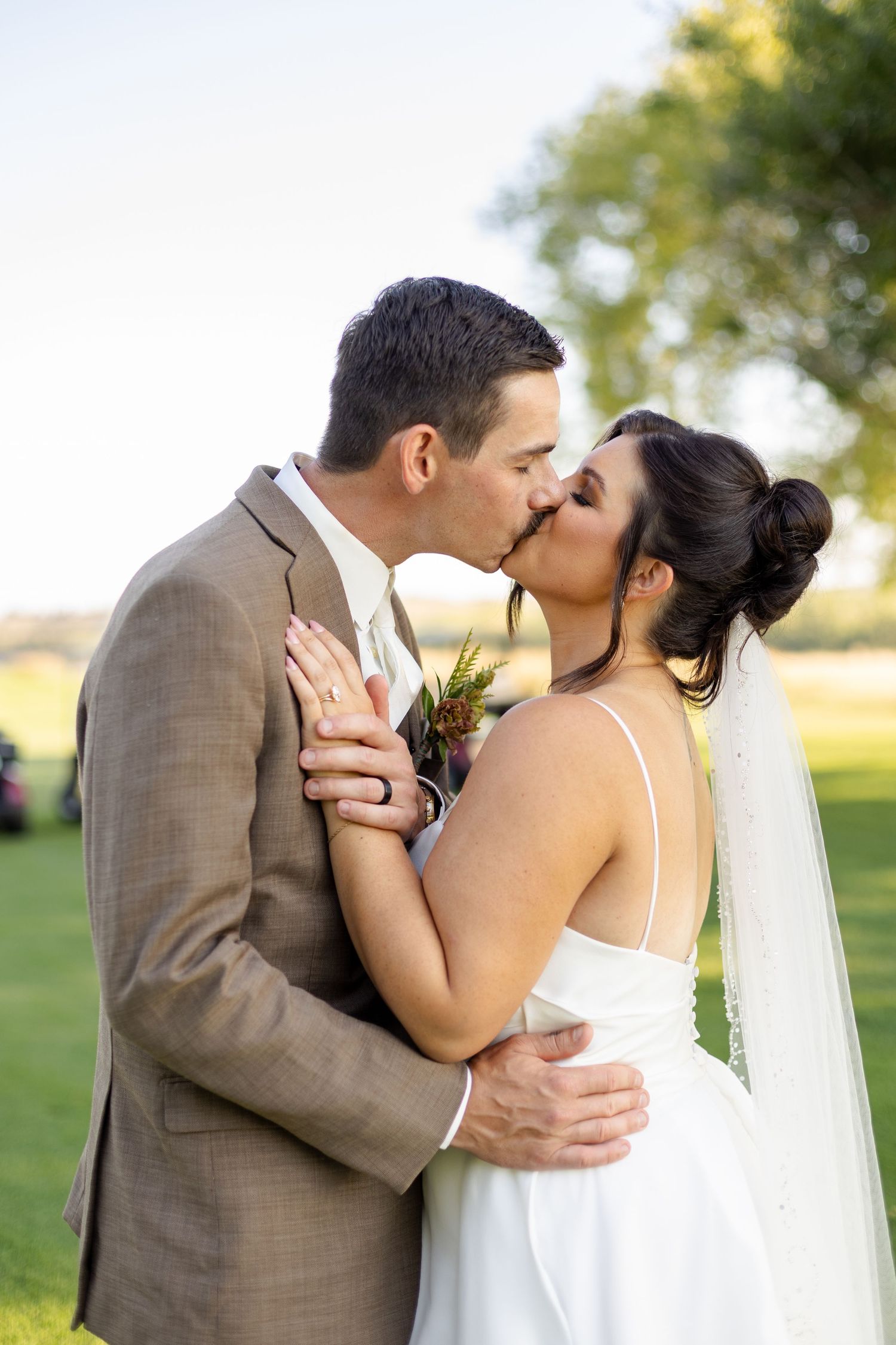 Romantic wedding portraits in golden sunlight with couple embracing outdoors.