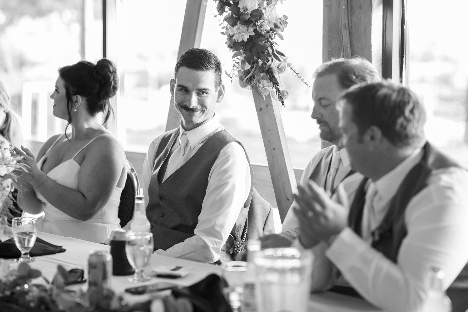 Black and white photo of wedding reception guests laughing and celebrating.