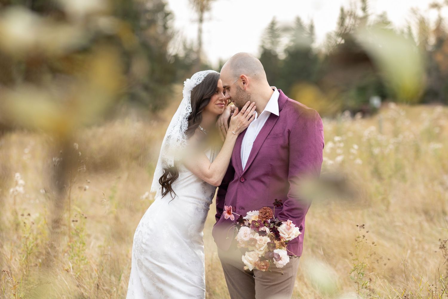 A couple shares romantic moments in a golden field during sunset while wearing wedding attire.