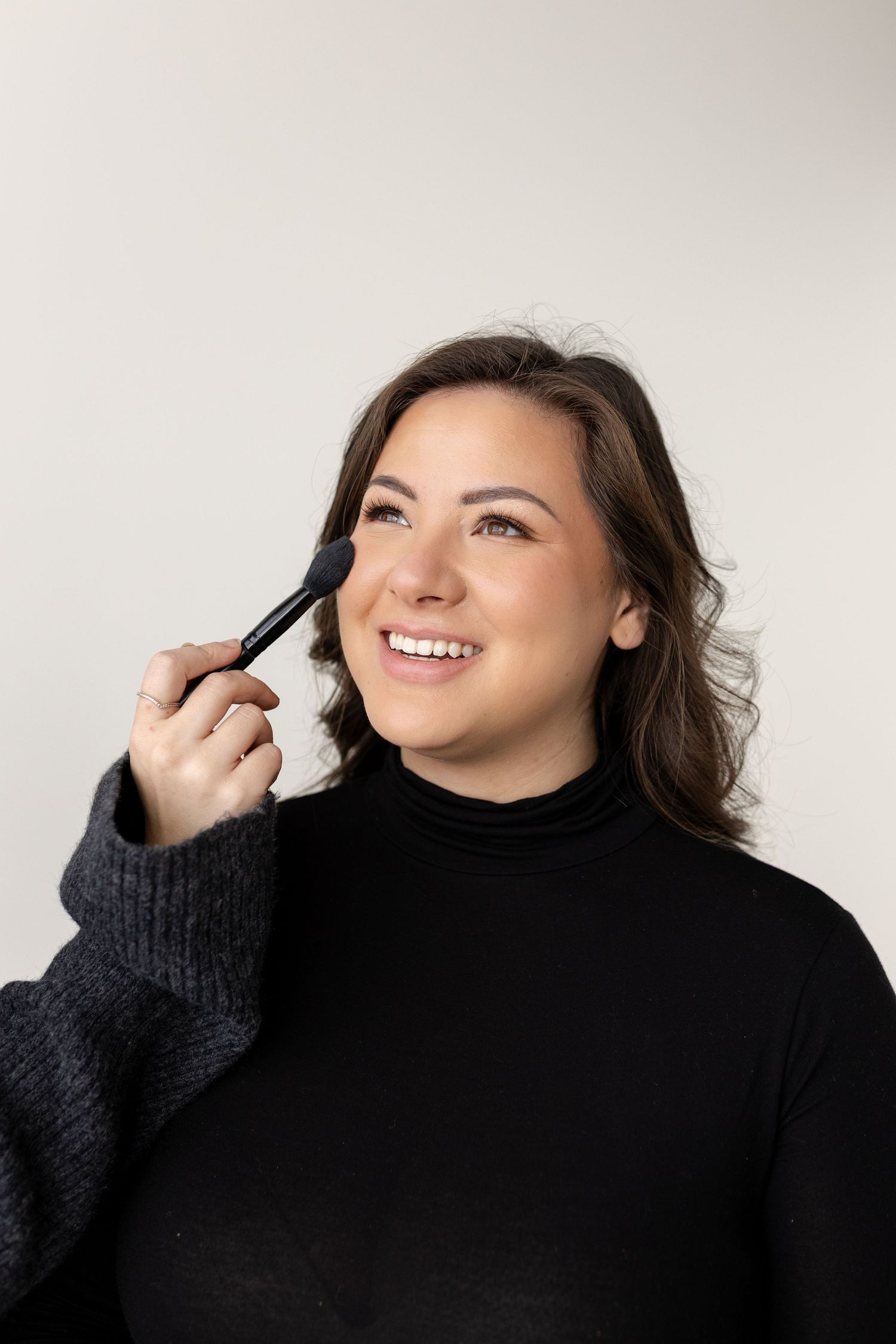 A series of four photos showing someone wearing a black turtleneck sweater against a white background.