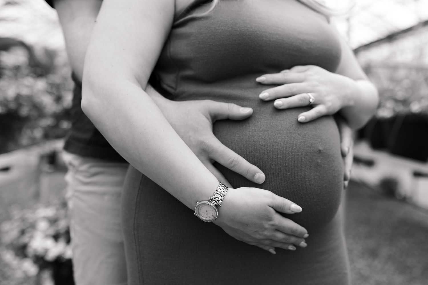 Black and white detail shot of hands lovingly placed on pregnant belly.