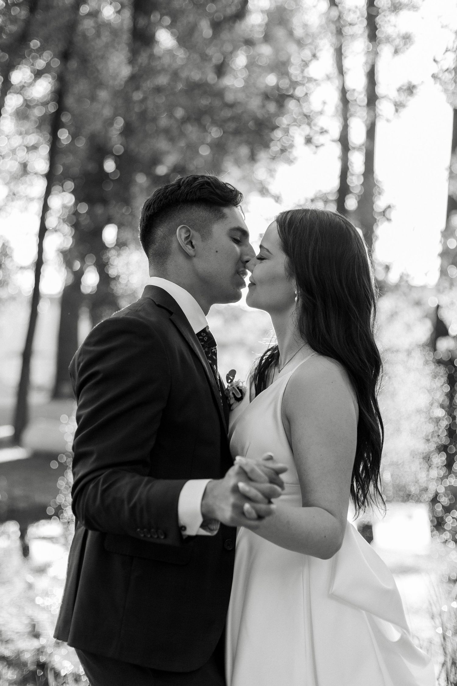 Black and white wedding portraits showing intimate moments between newlyweds in a forest setting.