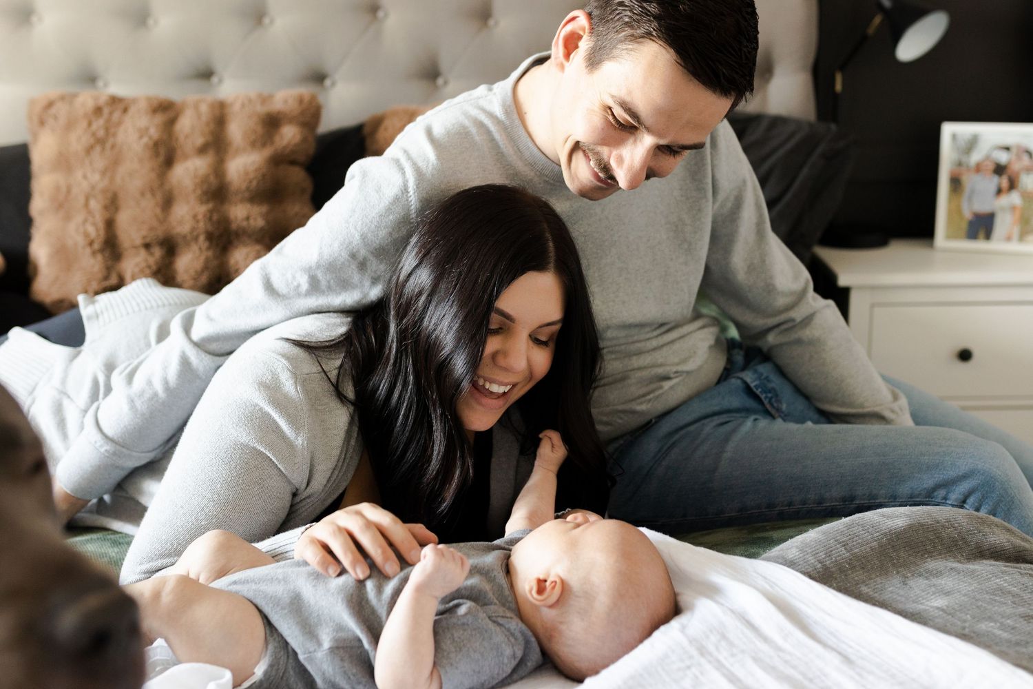 Family sharing intimate moments together on a plush tufted bed.