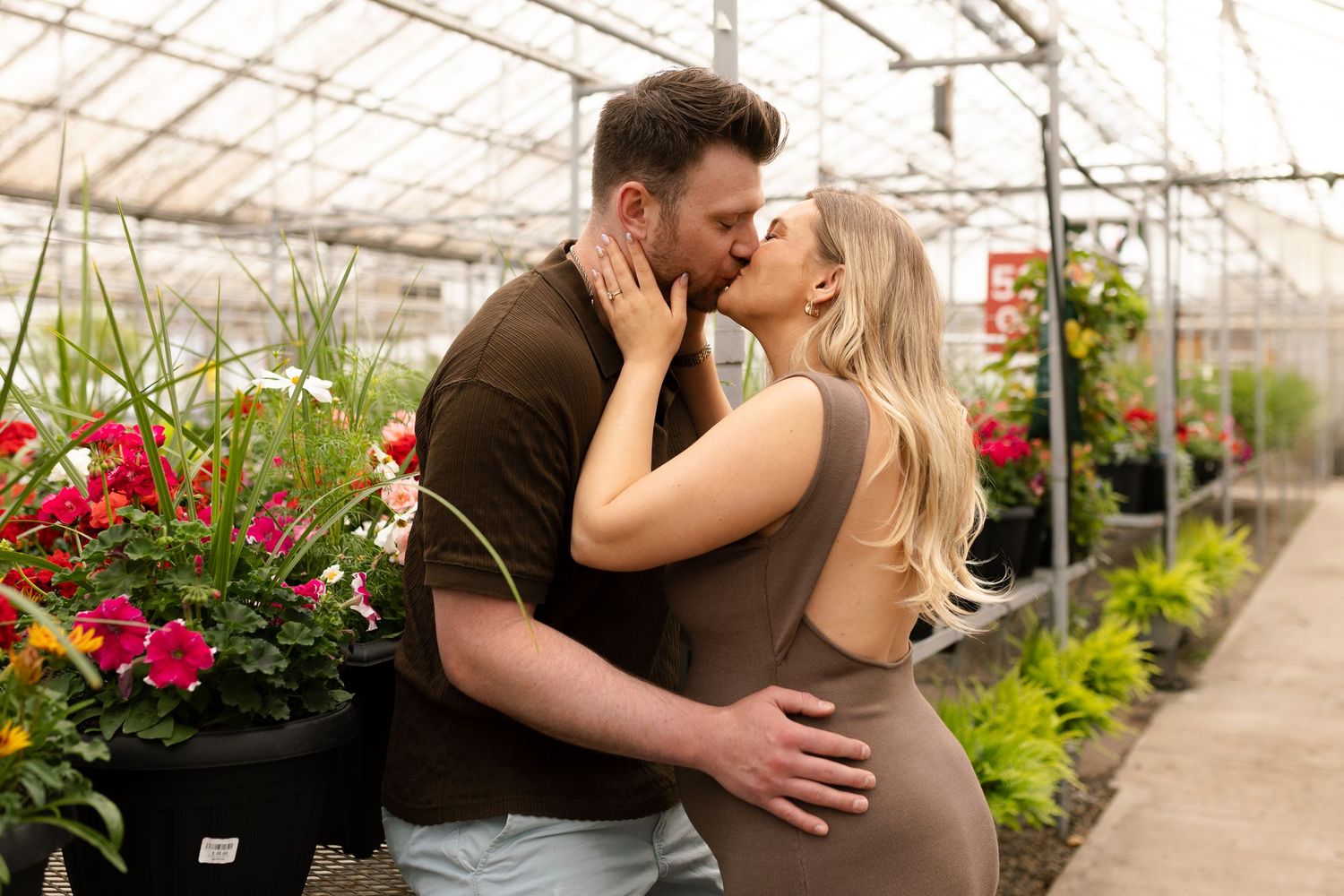 Tender greenhouse maternity photos with couple surrounded by blooming flowers and greenery.
