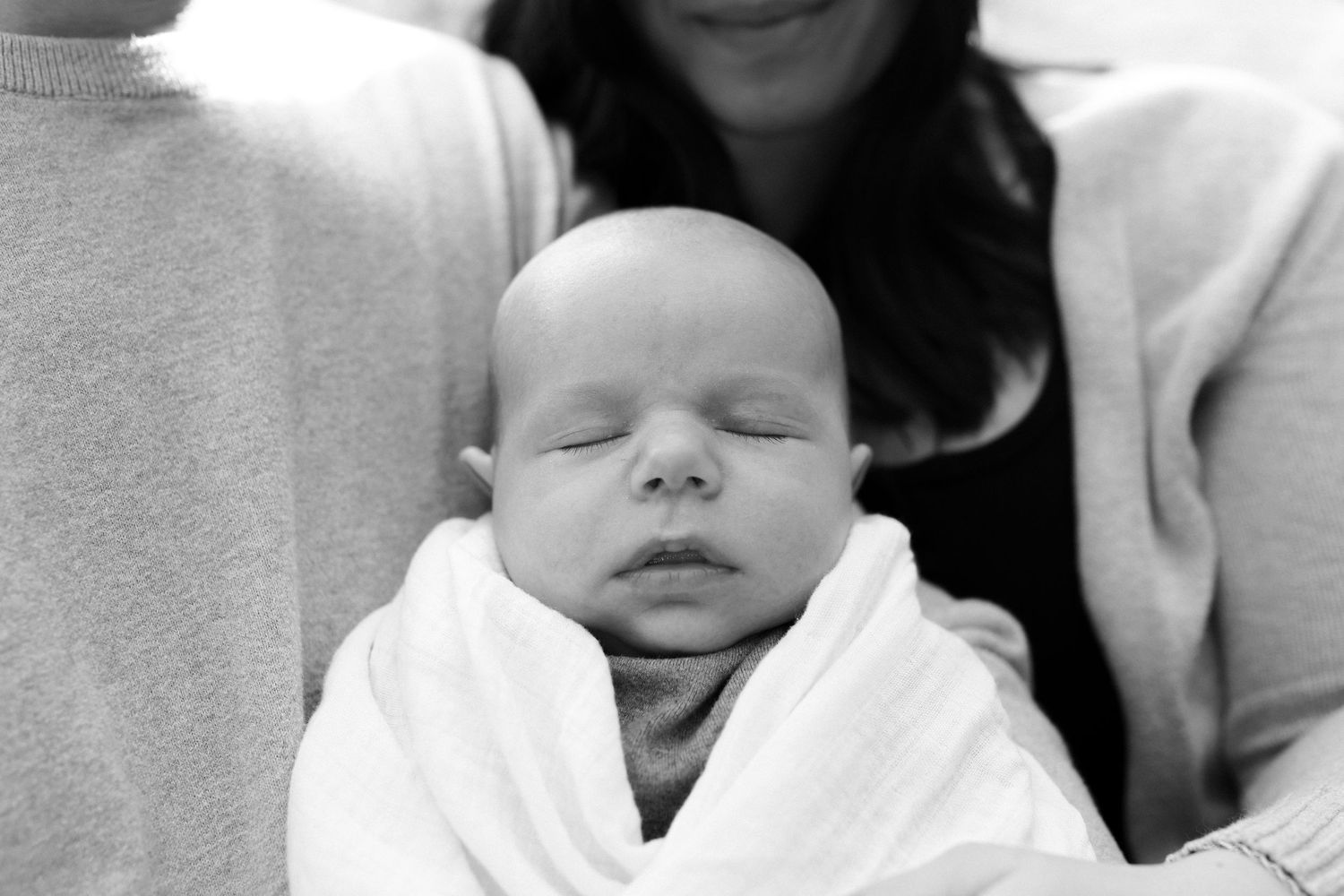 Black and white portraits capturing gentle moments with a sleeping newborn.