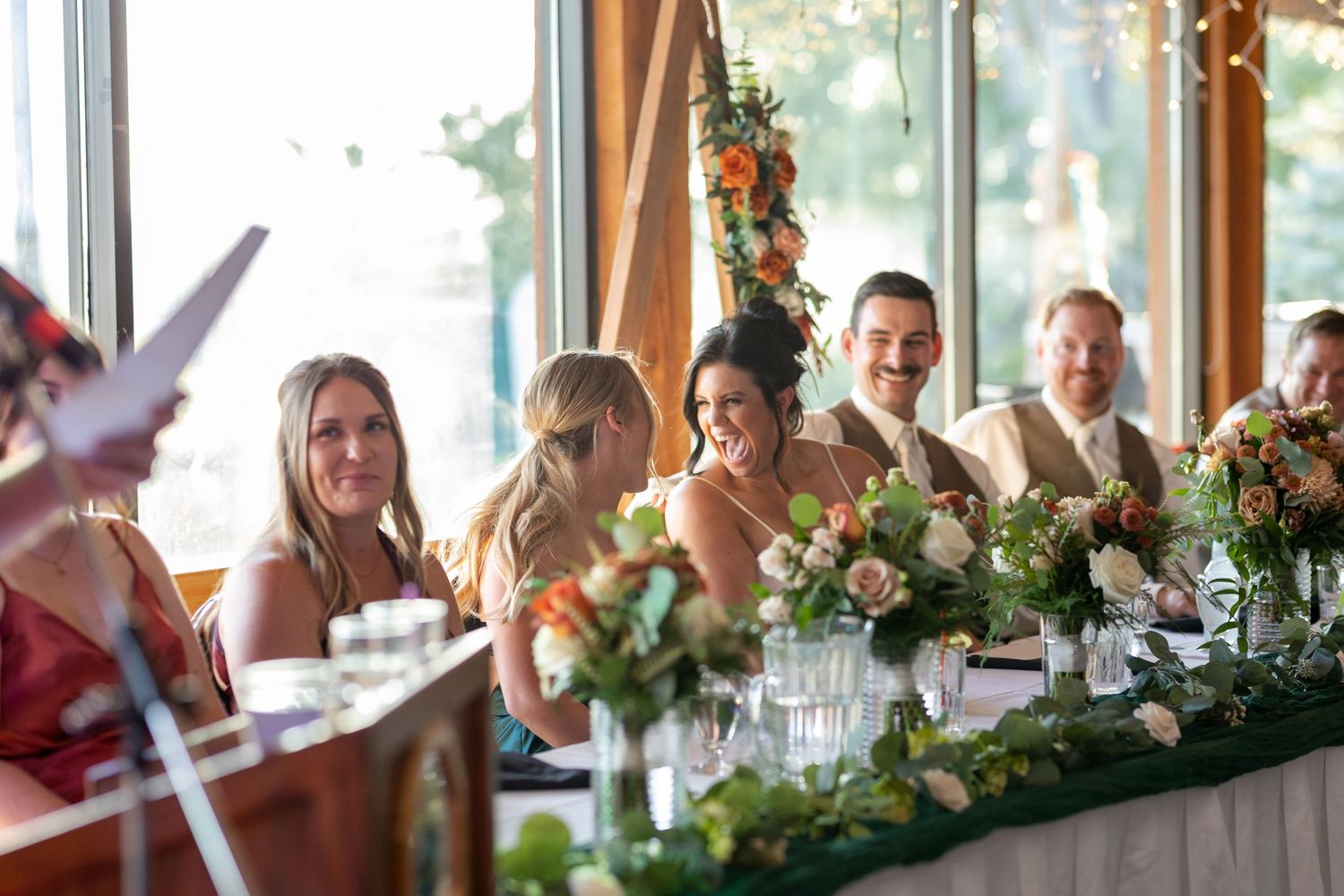 Wedding reception table decorated with floral centerpieces and place settings in a bright venue.