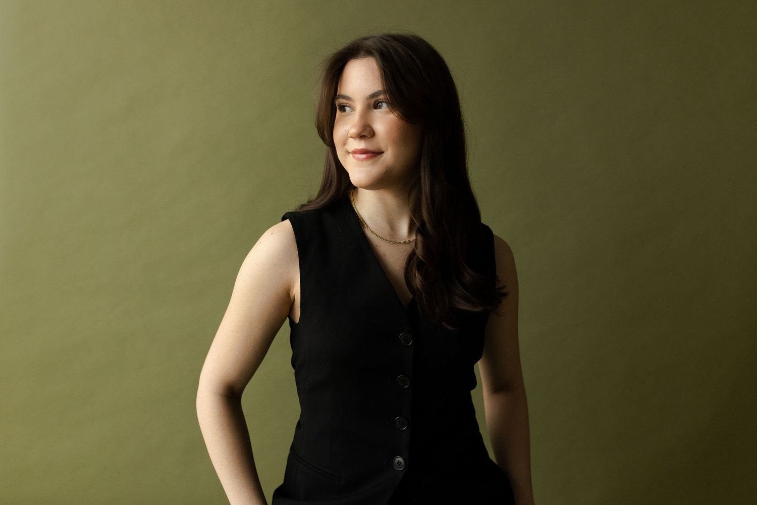 A fashion model in a black sleeveless top poses against a green background in a series of connected shots.