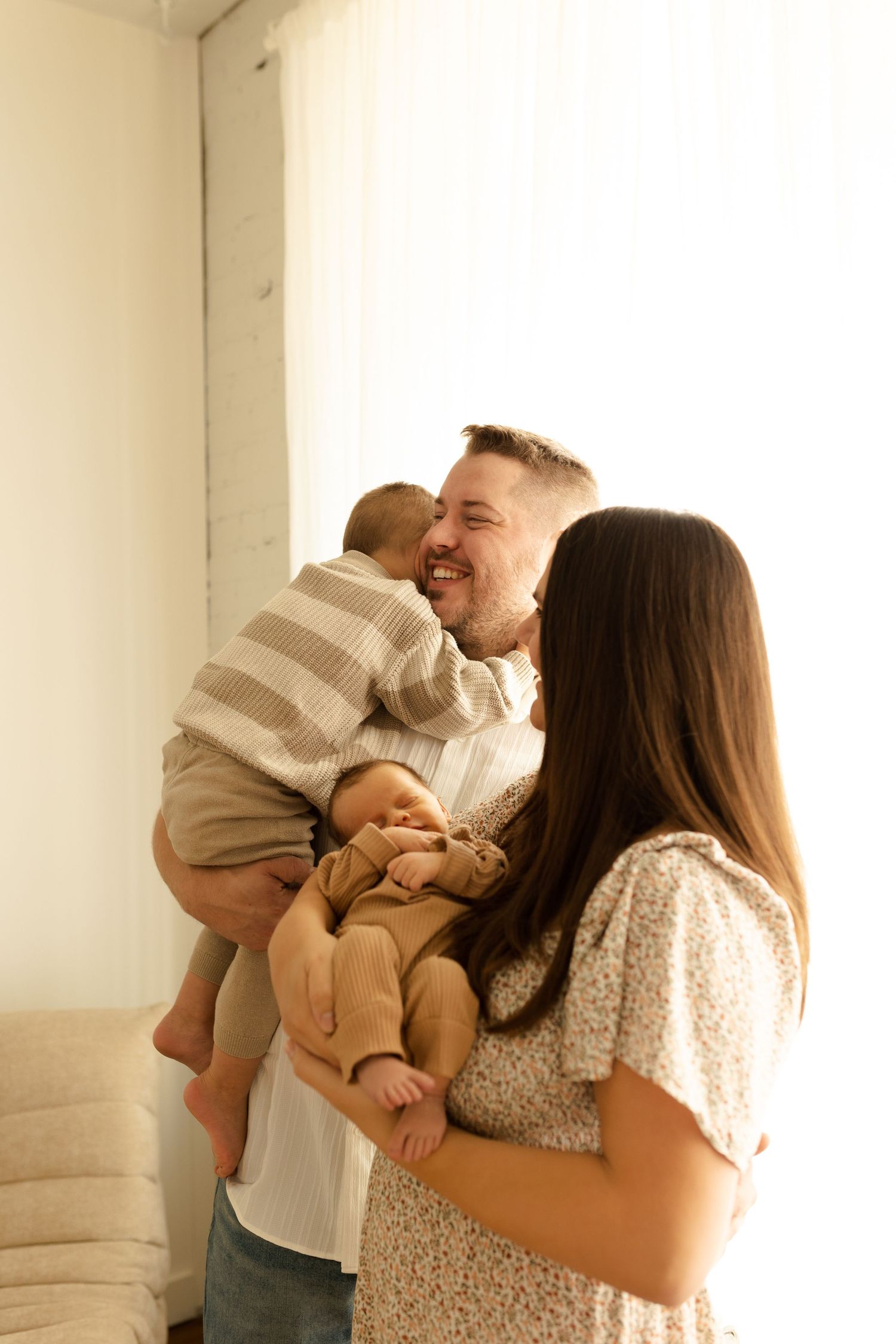 A couple shares joyful moments with their baby in a series of candid photos against a white wall.