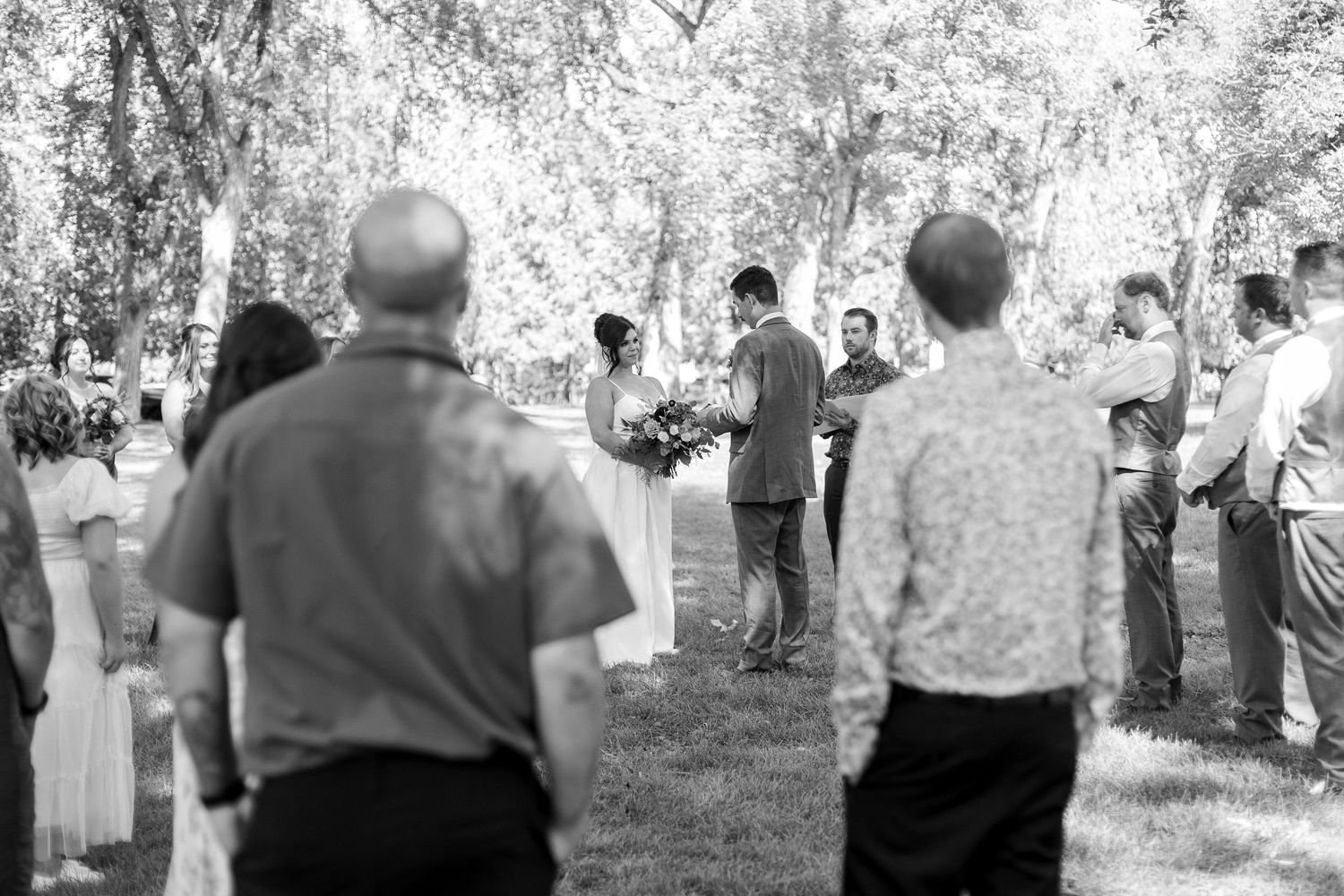 Black and white photo of wedding guests watching outdoor ceremony.