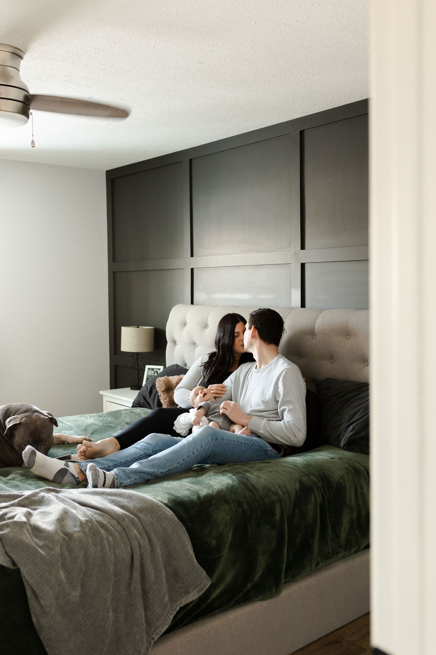 Family spending quality time together on a large bed with dark gray bedding.