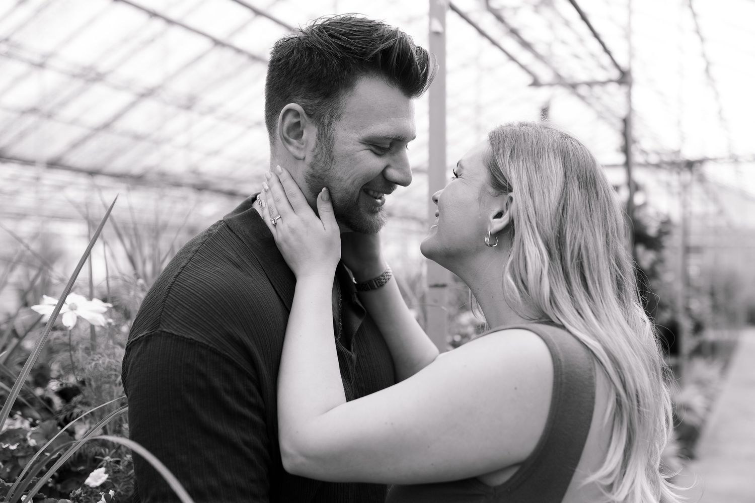 Black and white greenhouse maternity portraits showing couple's loving embrace.